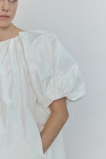 Editorial image of the white Kamperett Eva Dress cinched at the waist with the coordinating silk taffeta belt.