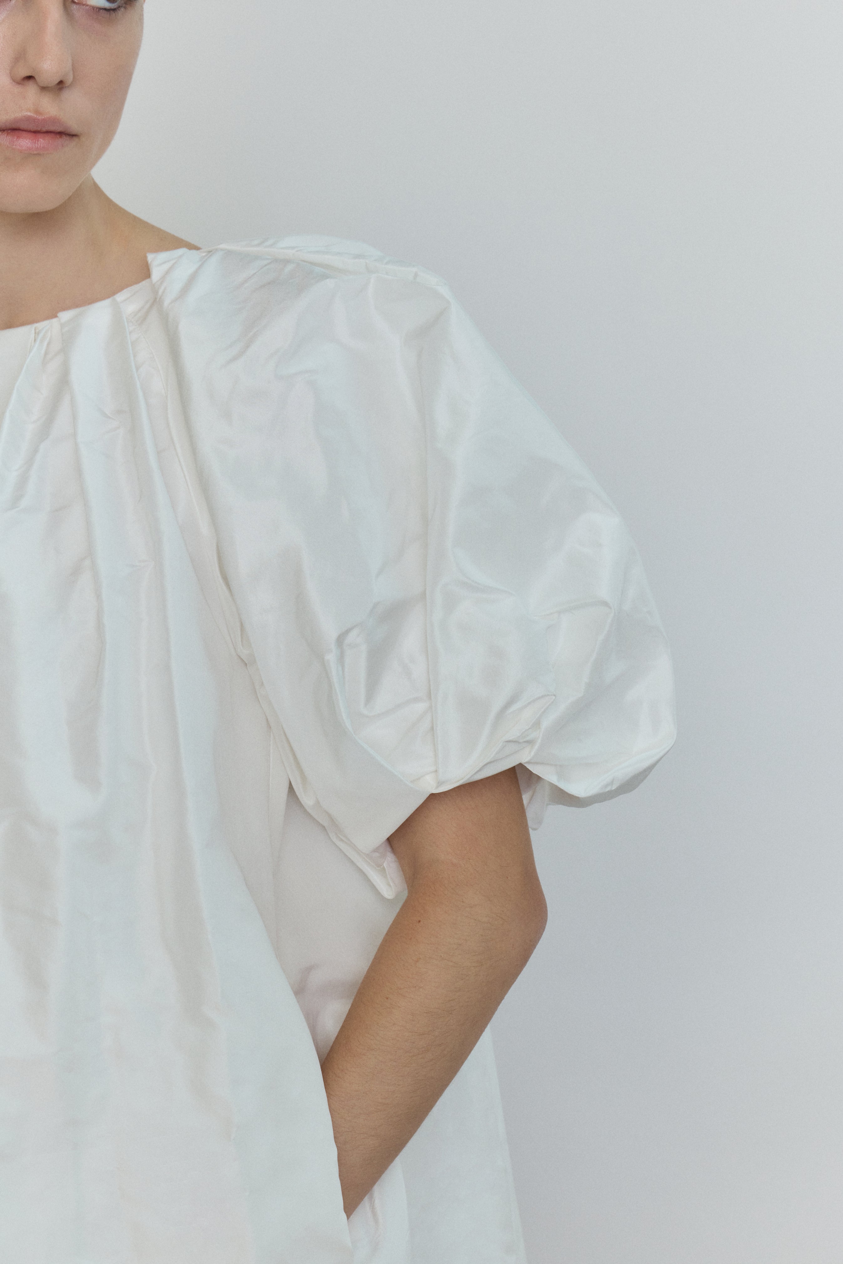 Editorial image of the white Kamperett Eva Dress cinched at the waist with the coordinating silk taffeta belt.