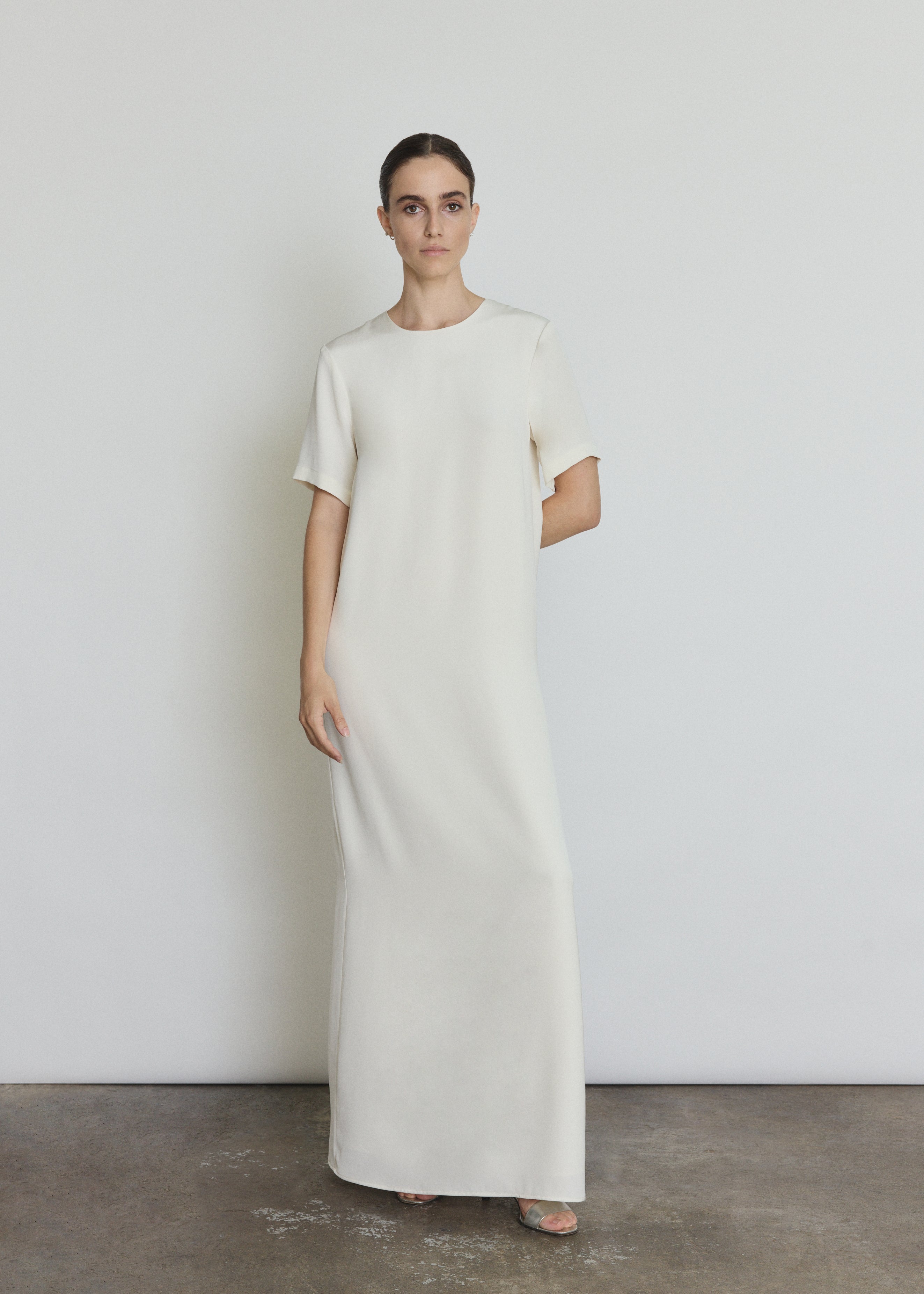 Front view of a bride wearing the alabaster silk crepe Kamperett Galerie Dress, a minimalist column wedding gown with clean crew neckline.