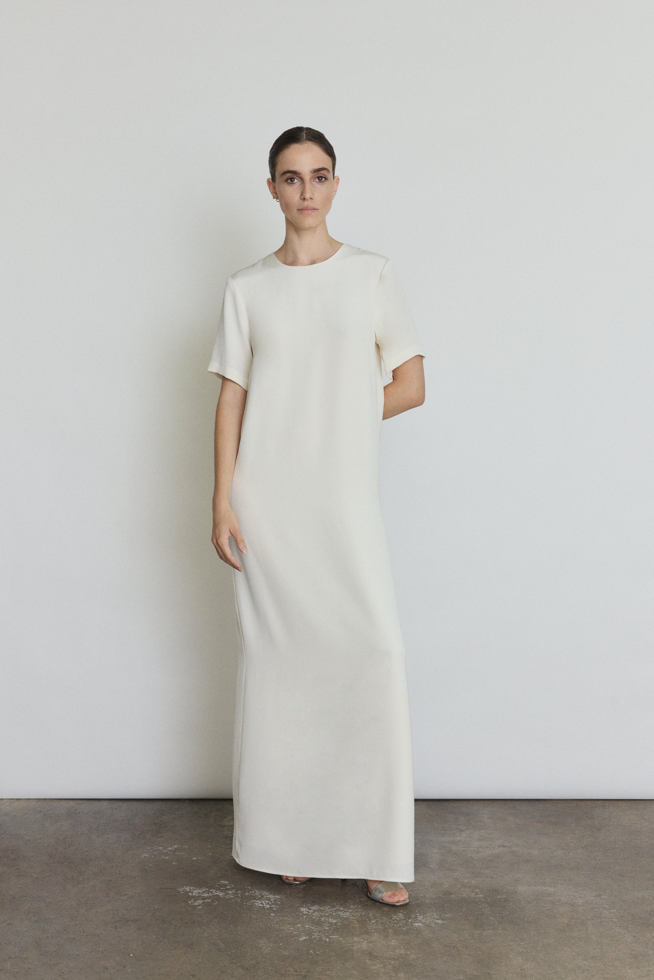 Front view of a bride wearing the alabaster silk crepe Kamperett Galerie Dress, a minimalist column wedding gown with clean crew neckline.