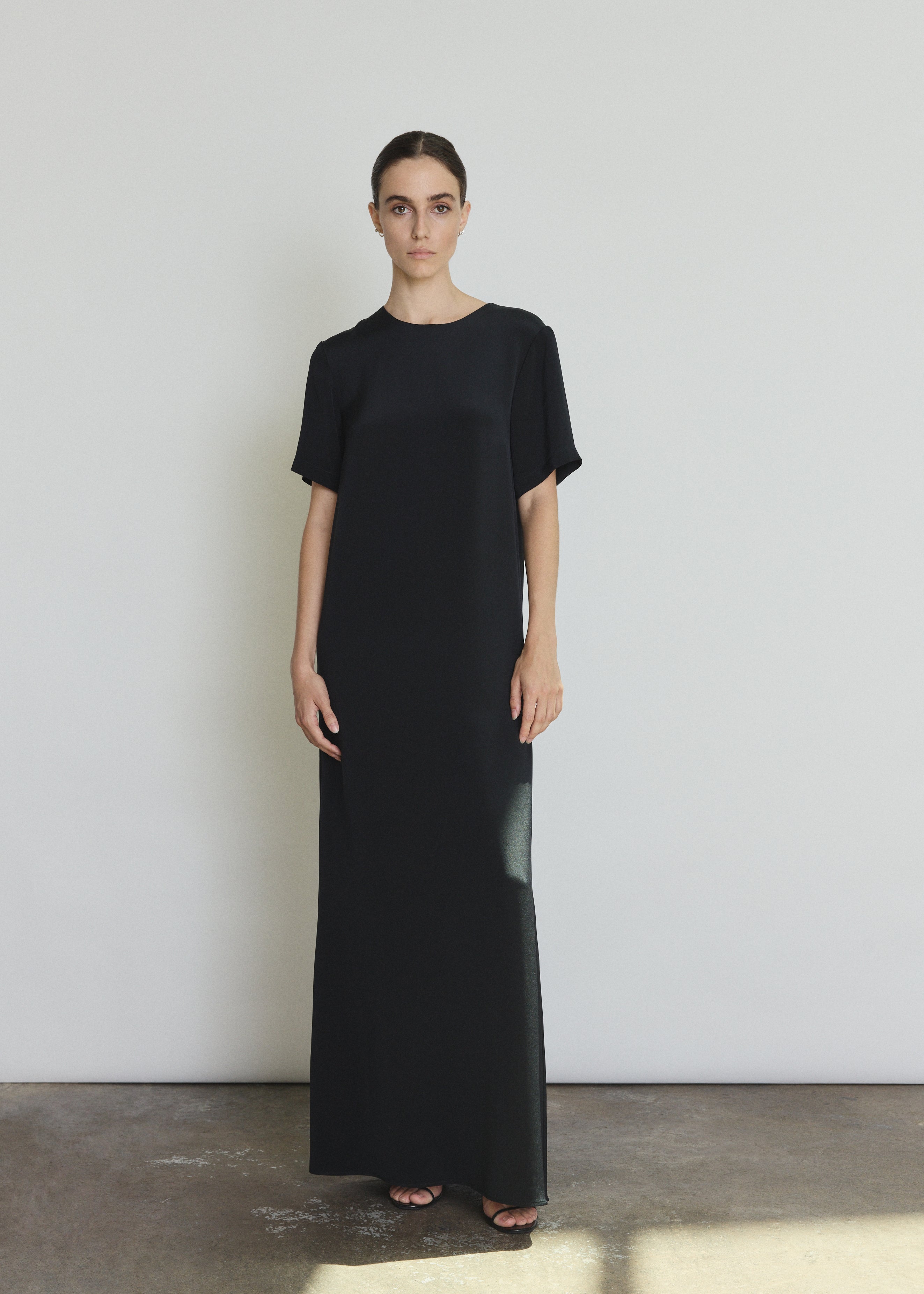 Front view of a model wearing the black silk crepe Kamperett Galerie Dress, a minimalist column gown with clean crew neckline.