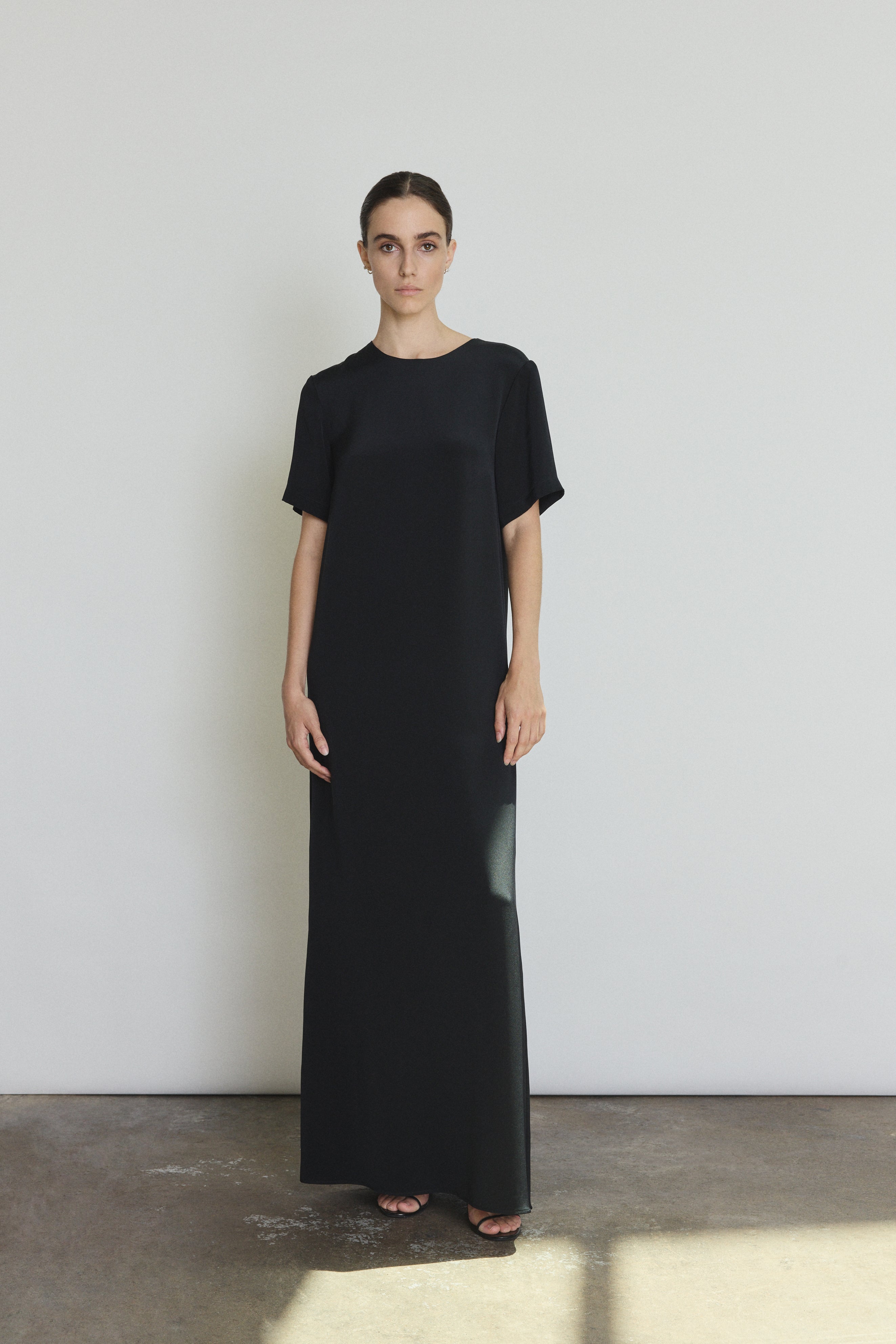 Front view of a model wearing the black silk crepe Kamperett Galerie Dress, a minimalist column gown with clean crew neckline.