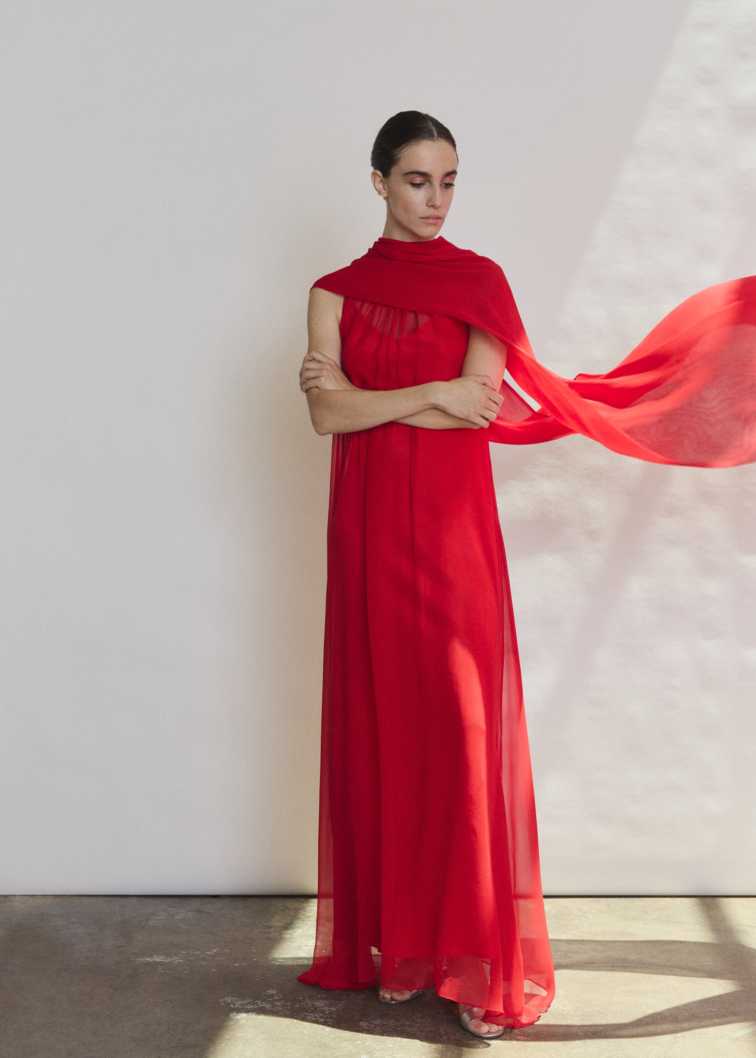 Editorial image of a model wearing the crimson Kamperett Iris Gown layered over the Caroline Slip Dress in Crimson.