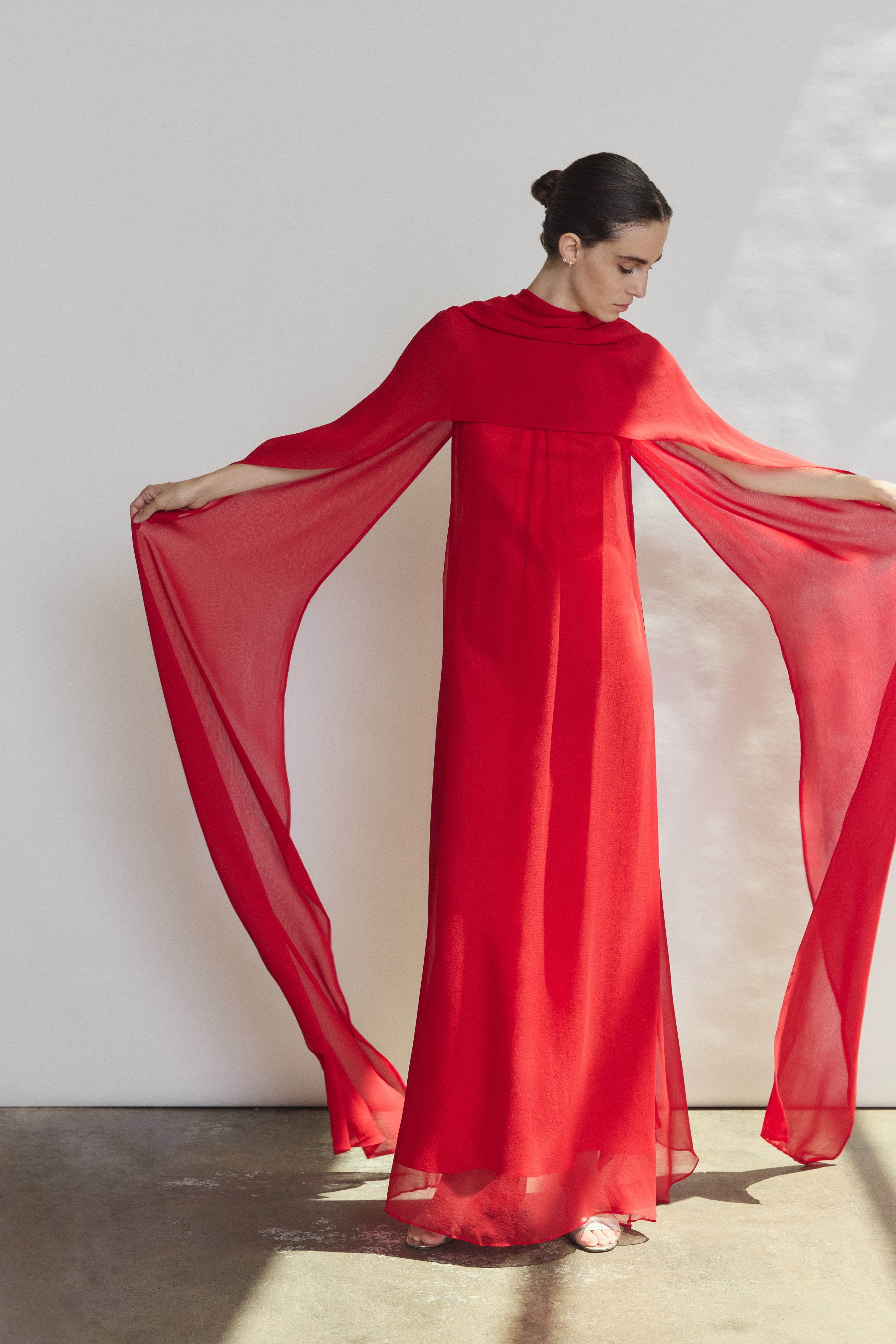 Editorial image of the crimson Kamperett Iris Gown with the capelet draped to reveal the shoulders.