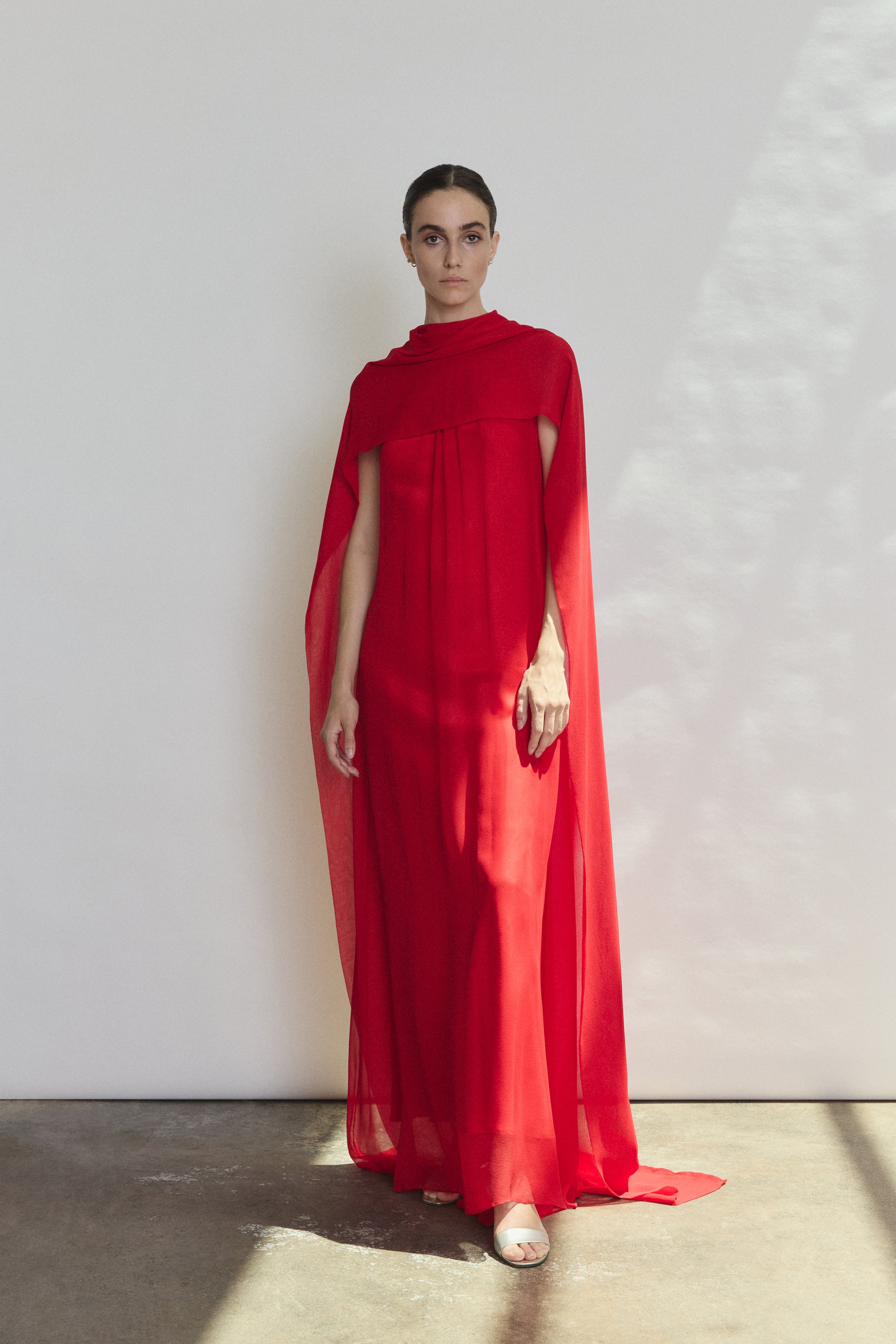 Side view of the crimson silk chiffon Kamperett Iris Gown showing the floating capelet.