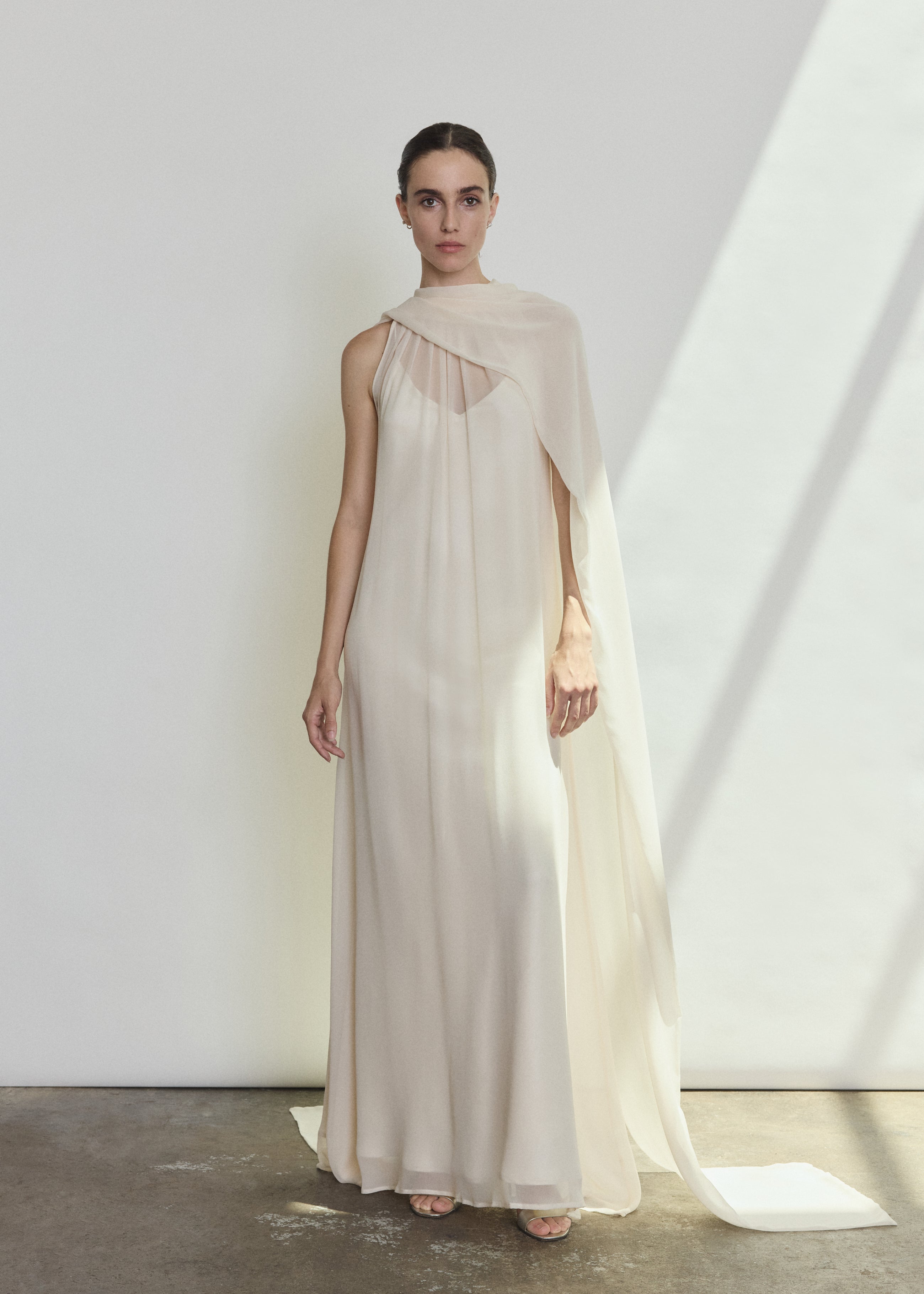 Front view of a bride wearing the ivory silk chiffon Kamperett Iris Gown, a scarf-neck column wedding gown with integrated capelet.