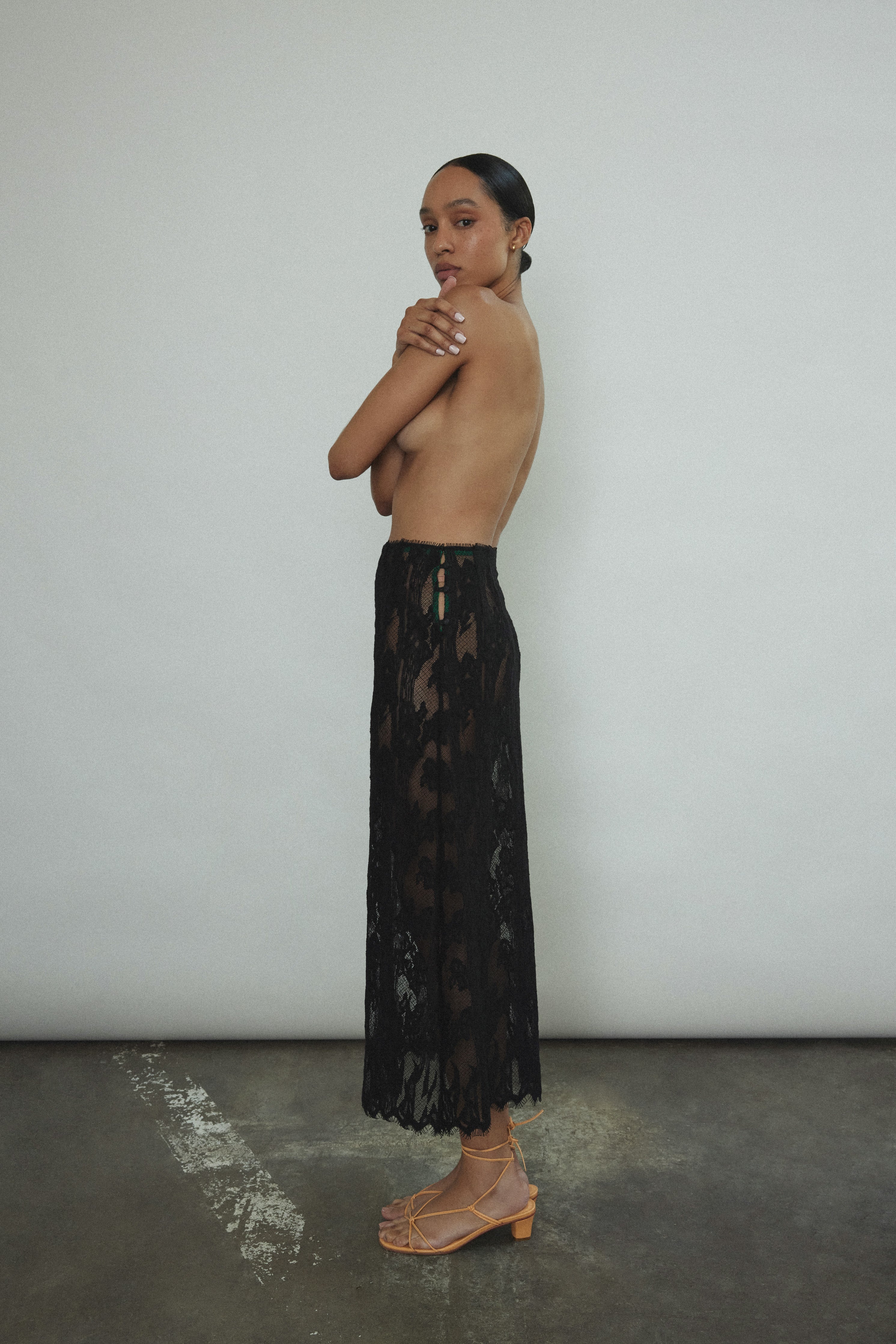 Side view of the black French lace Kamperett Isabella Skirt showing the straight-cut silhouette and eyelash lace hem.