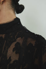 Kamperett Isabella Tunic in black French lace, editorial close-up of structured mock neck and button closure at shoulder seam.