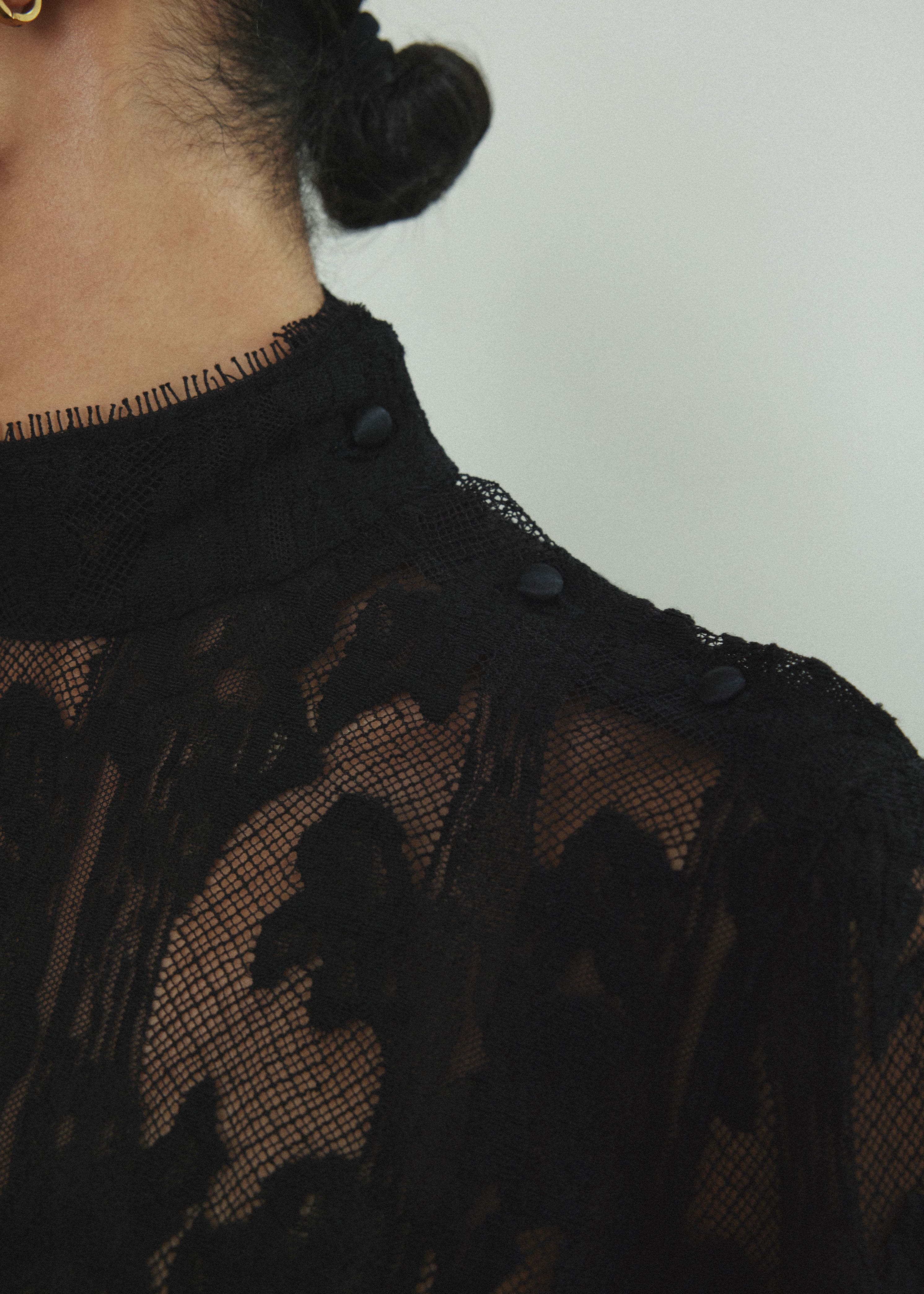 Close-up of the mock neck and shoulder-seam button closure on the black French lace Kamperett Isabella Tunic.