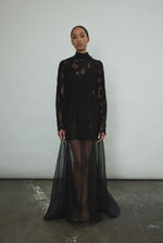 Kamperett Isabella Tunic in black French lace, full-length front view showing straight-cut silhouette, mock neck, eyelash lace hem, and long sleeves with wrist zipper closure.