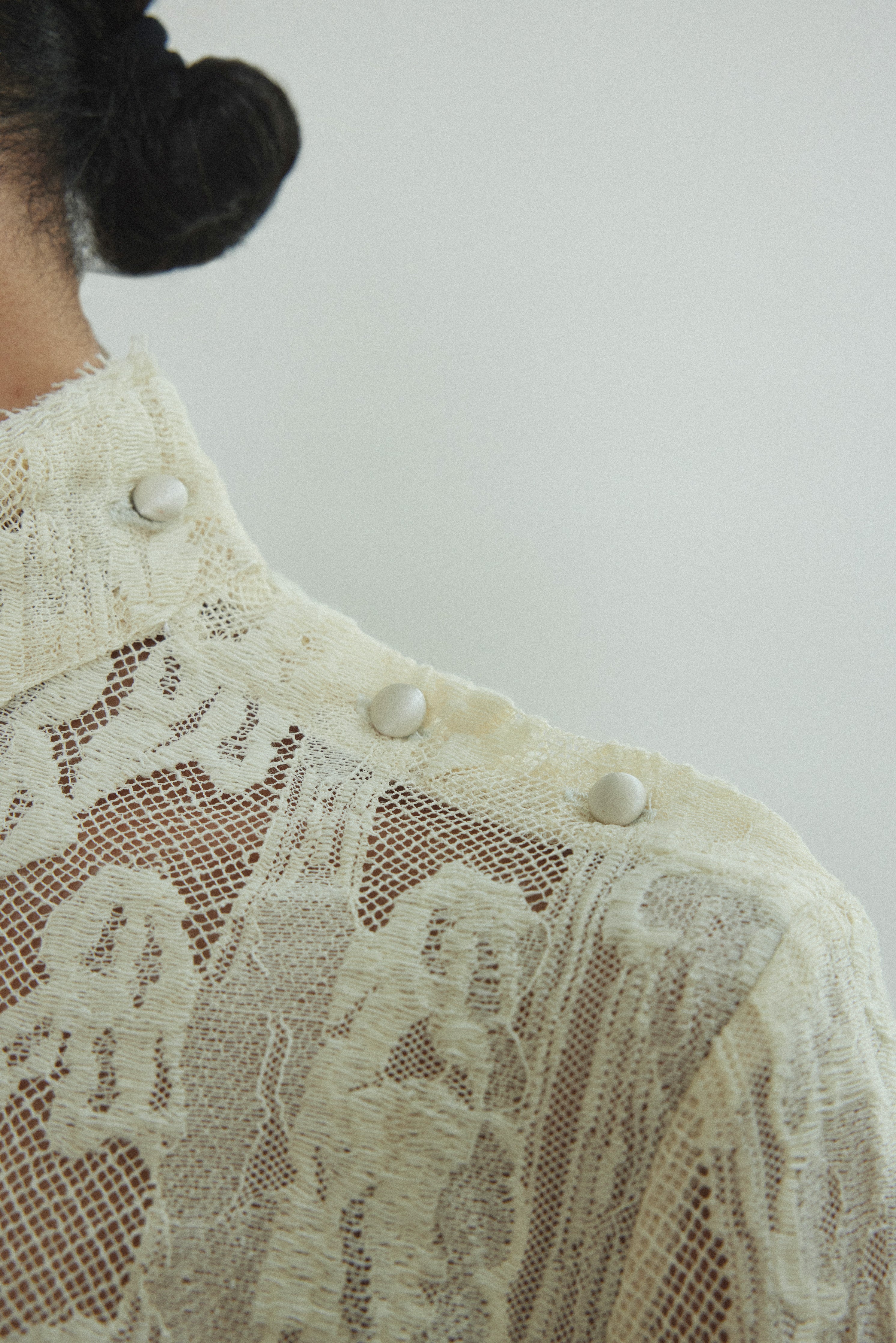 Kamperett Isabella Tunic in cream French lace, editorial close-up of structured mock neck and button closure at shoulder seam.