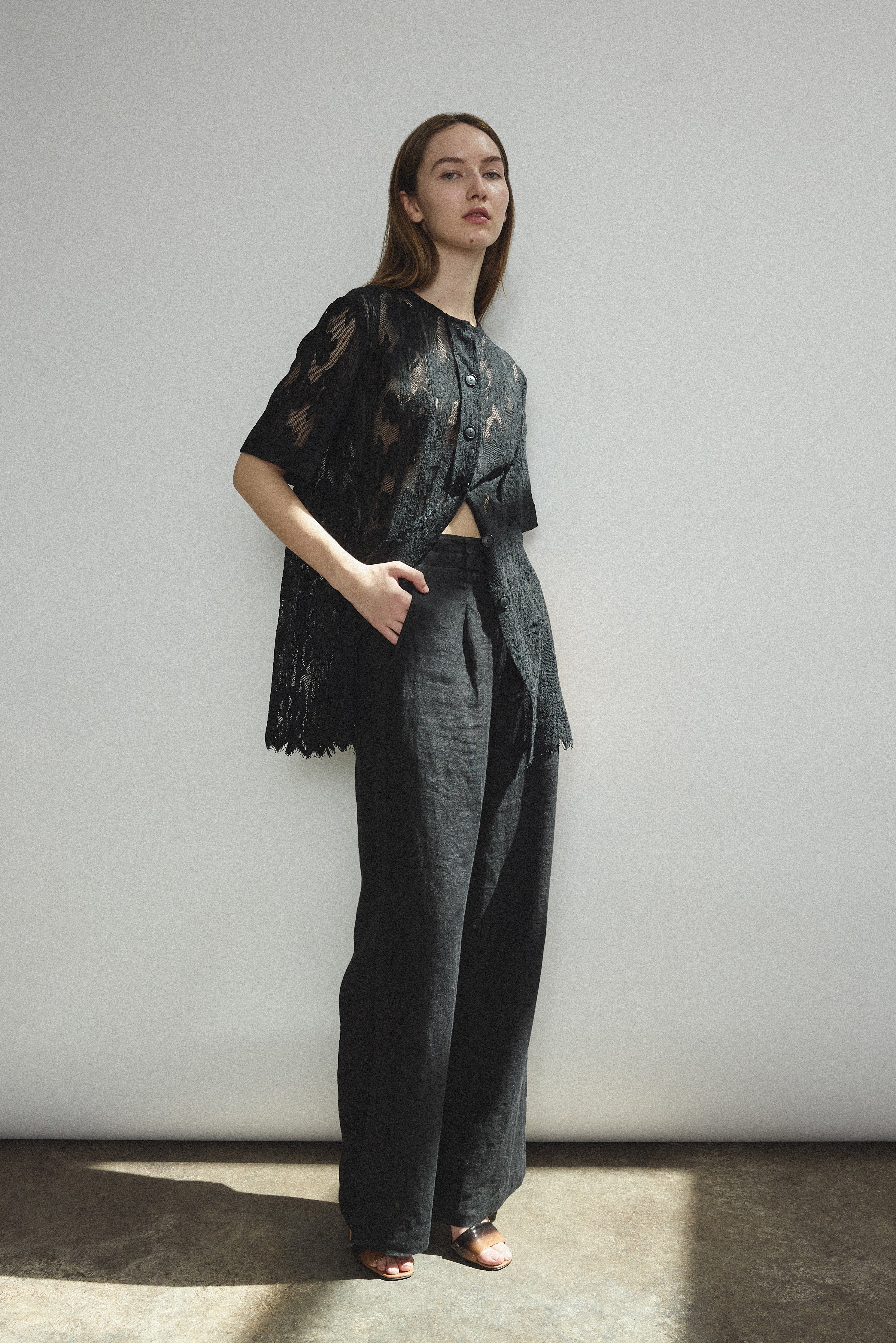 Angled view of the black French lace Kamperett Jette Tee with oversized reversible cut.
