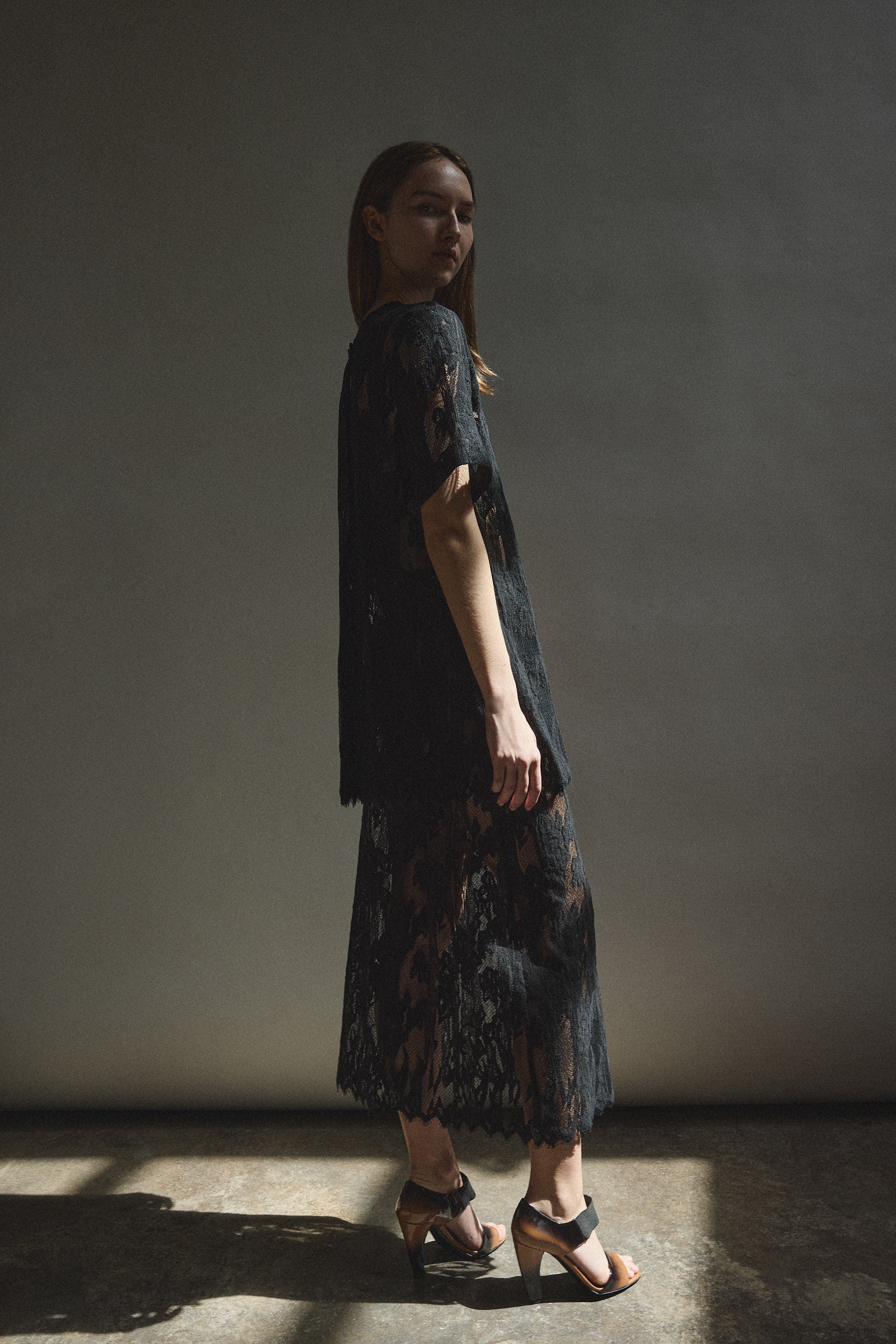 Editorial image of a model in the black French lace Kamperett Jette Tee.