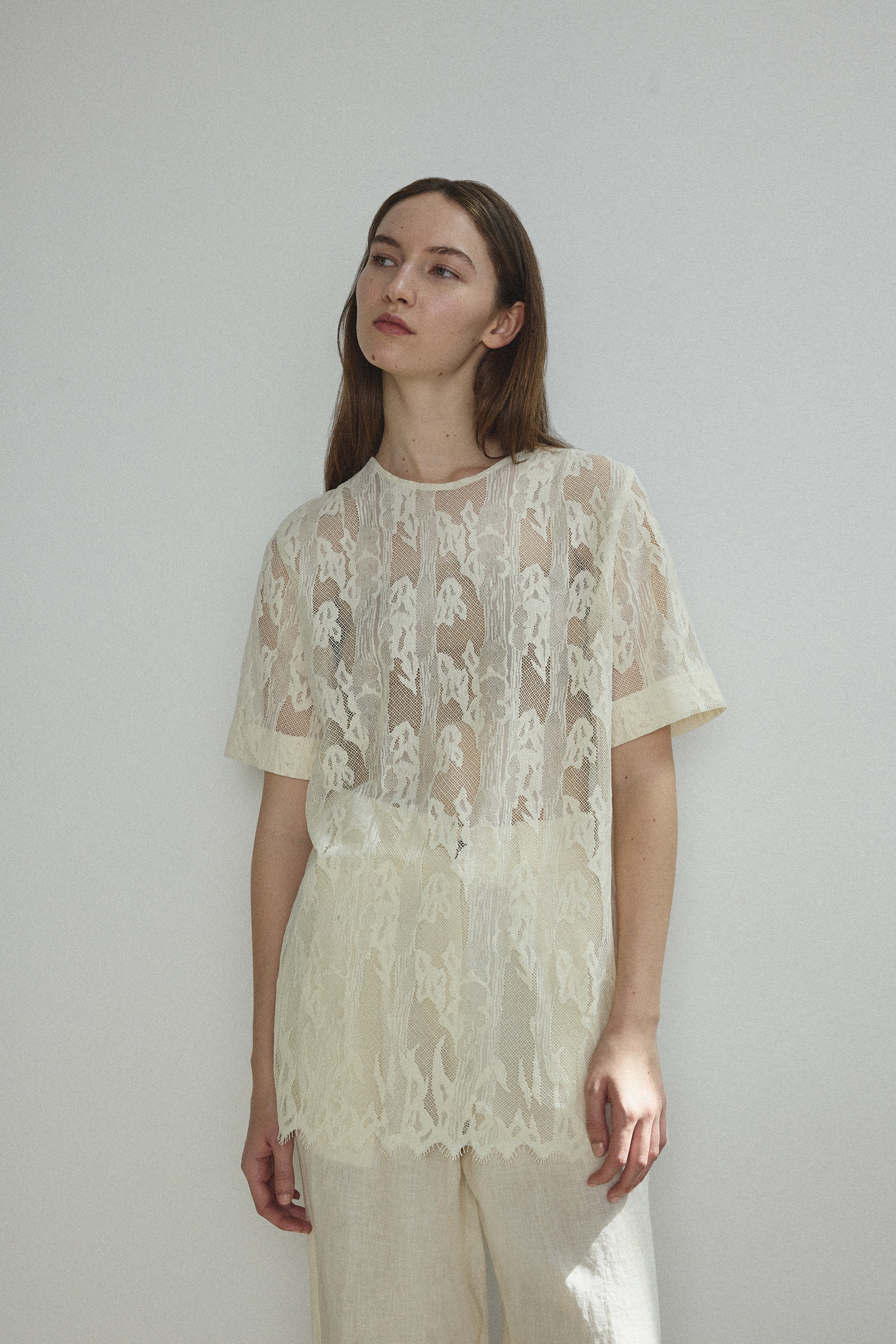 Editorial image of a model in the cream French lace Kamperett Jette Tee.