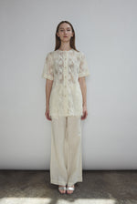 Front view of a model wearing the cream French lace Kamperett Jette Tee with wide button placket and shoulder darts.