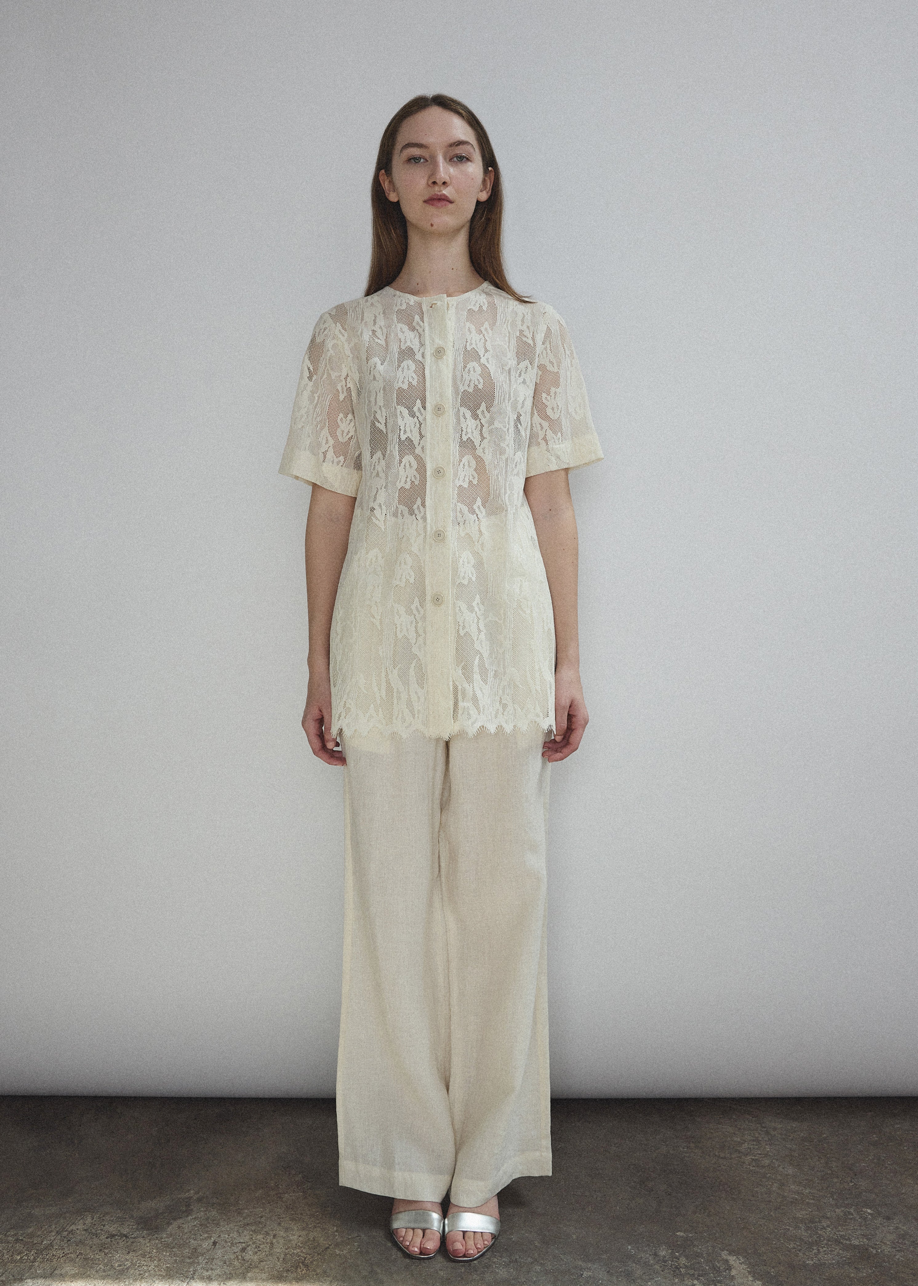 Front view of a model wearing the cream French lace Kamperett Jette Tee with wide button placket and shoulder darts.