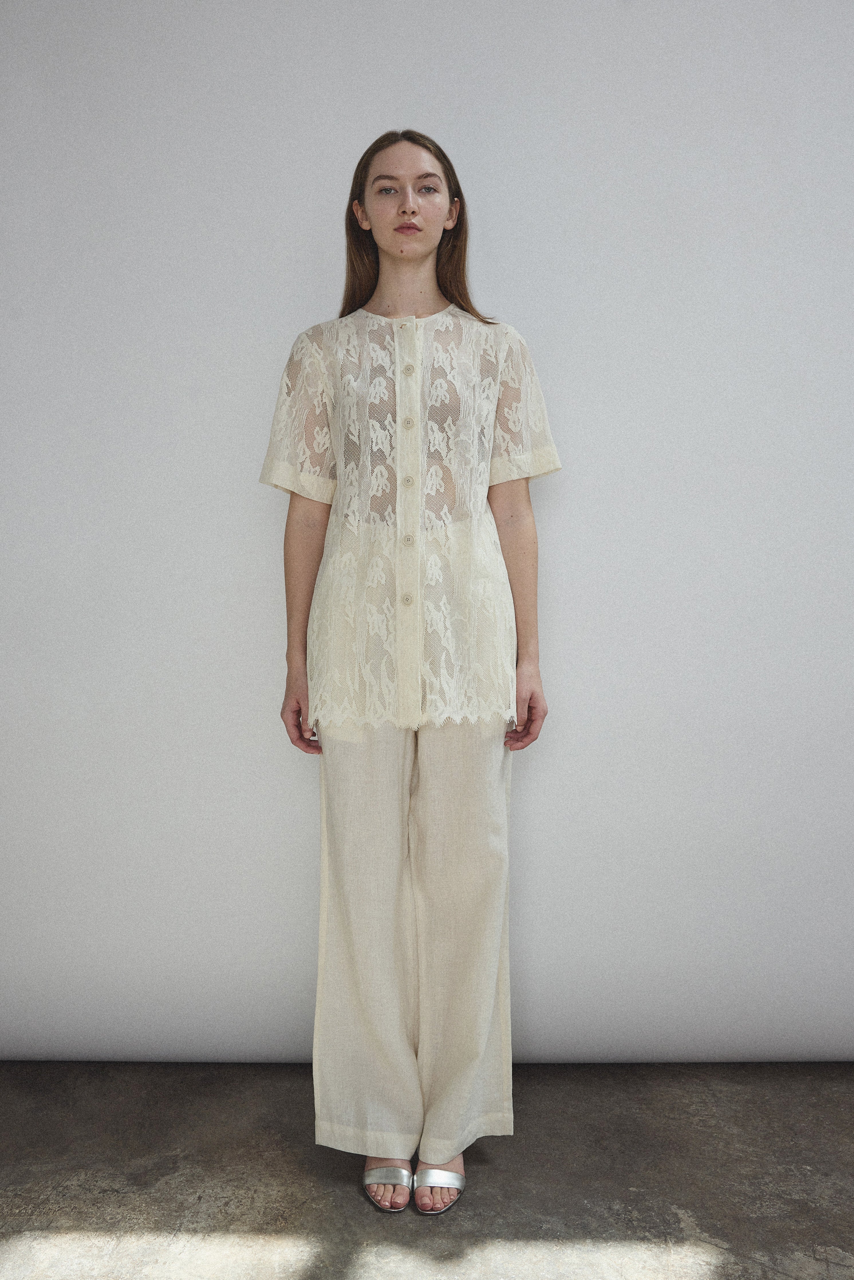 Front view of a model wearing the cream French lace Kamperett Jette Tee with wide button placket and shoulder darts.