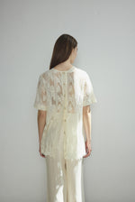 Motion shot of the cream French lace Kamperett Jette Tee, capturing the fluid drape.