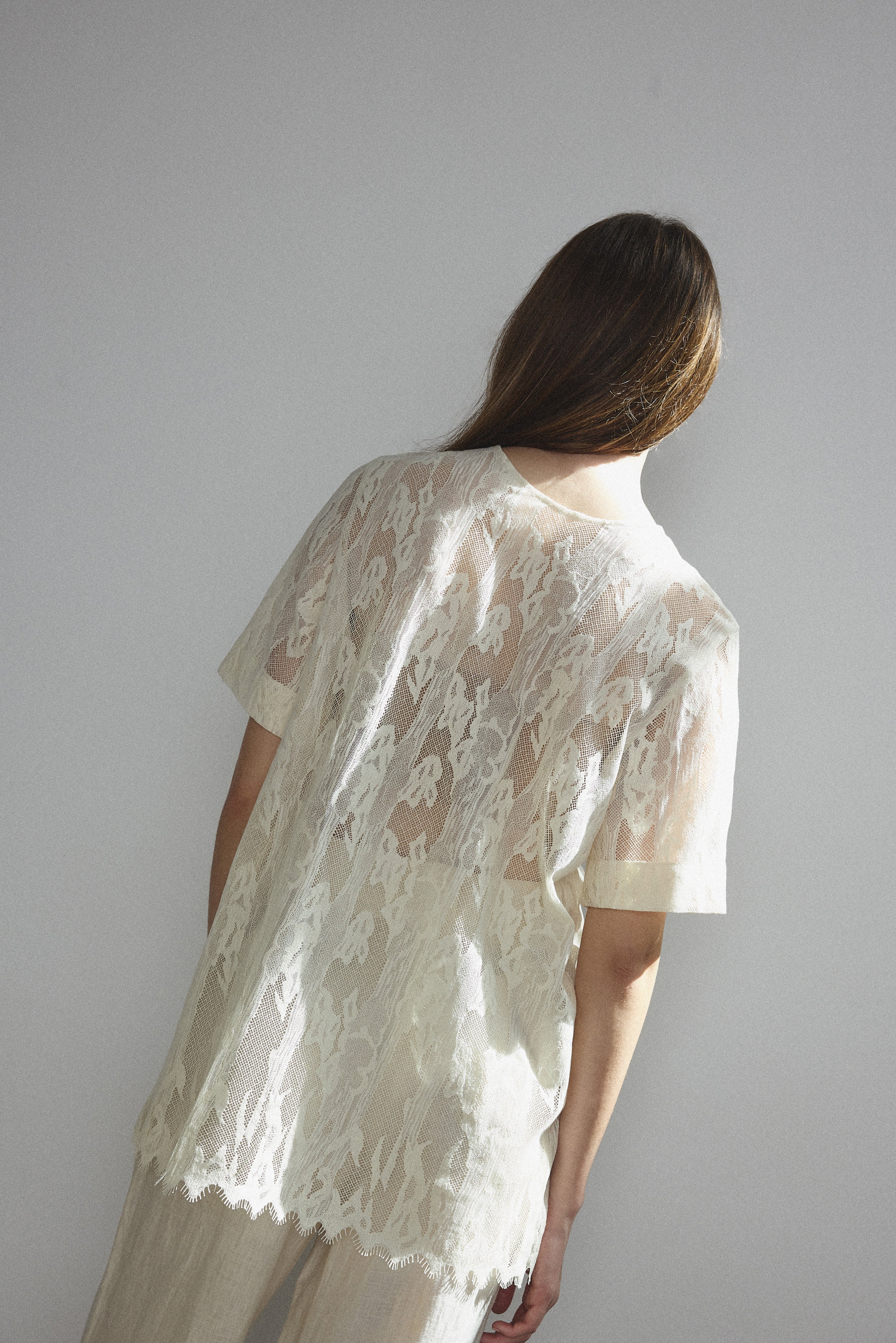 Detail of the wide button placket on the cream French lace Kamperett Jette Tee.