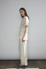 Angled view of the cream French lace Kamperett Jette Tee styled with the Huene Pant.