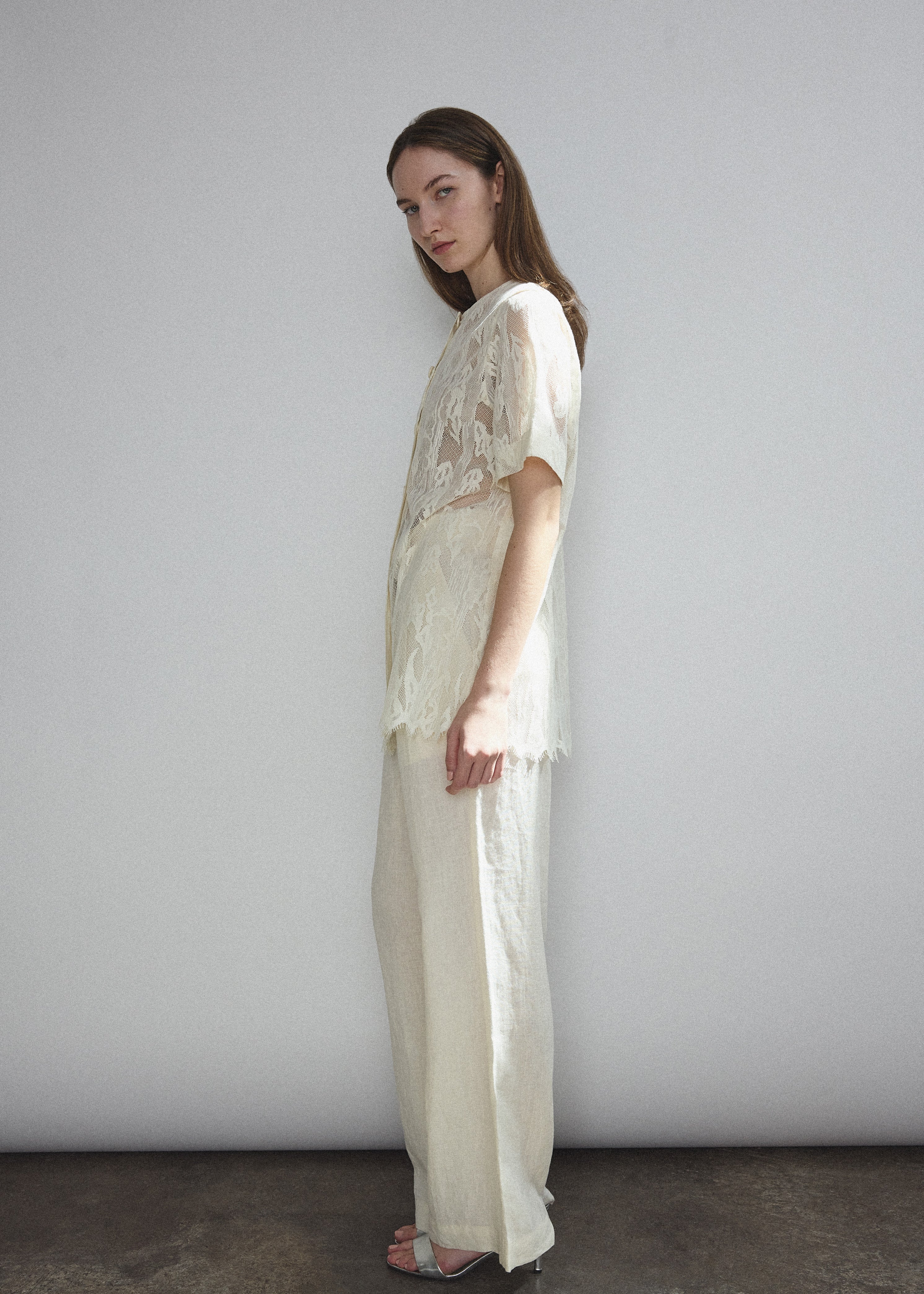Angled view of the cream French lace Kamperett Jette Tee styled with the Huene Pant.