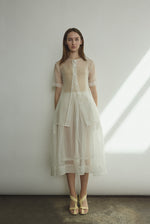 Front view of a bride wearing the alabaster silk organza Kamperett Jette Tee, an oversized reversible top with wide button placket.