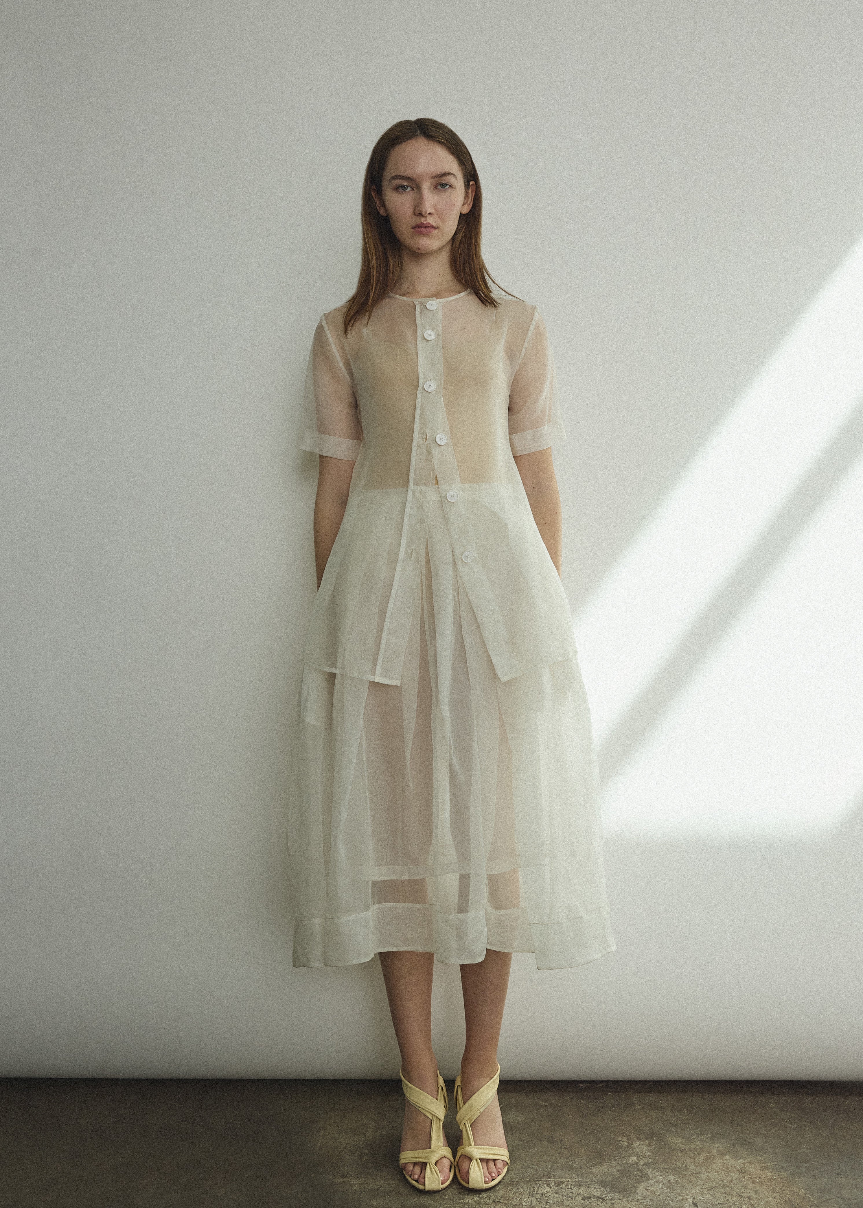 Front view of a bride wearing the alabaster silk organza Kamperett Jette Tee, an oversized reversible top with wide button placket.
