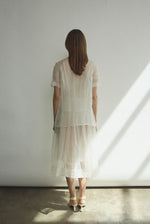 Motion shot of the alabaster silk organza Kamperett Jette Tee, capturing the sheer fluid drape.