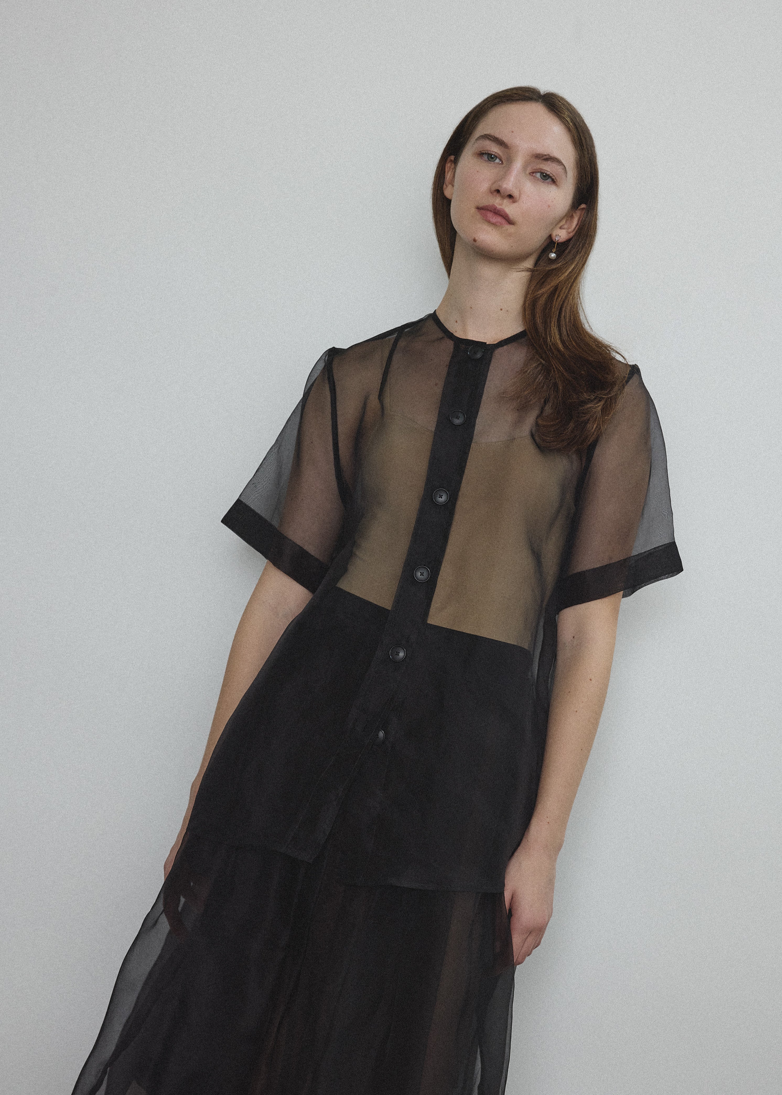 Front view of a model wearing the black silk organza Kamperett Jette Tee, an oversized reversible top with wide button placket.