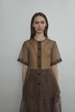 Front view of a model wearing the mushroom silk organza Kamperett Jette Tee, an oversized reversible top with wide button placket.