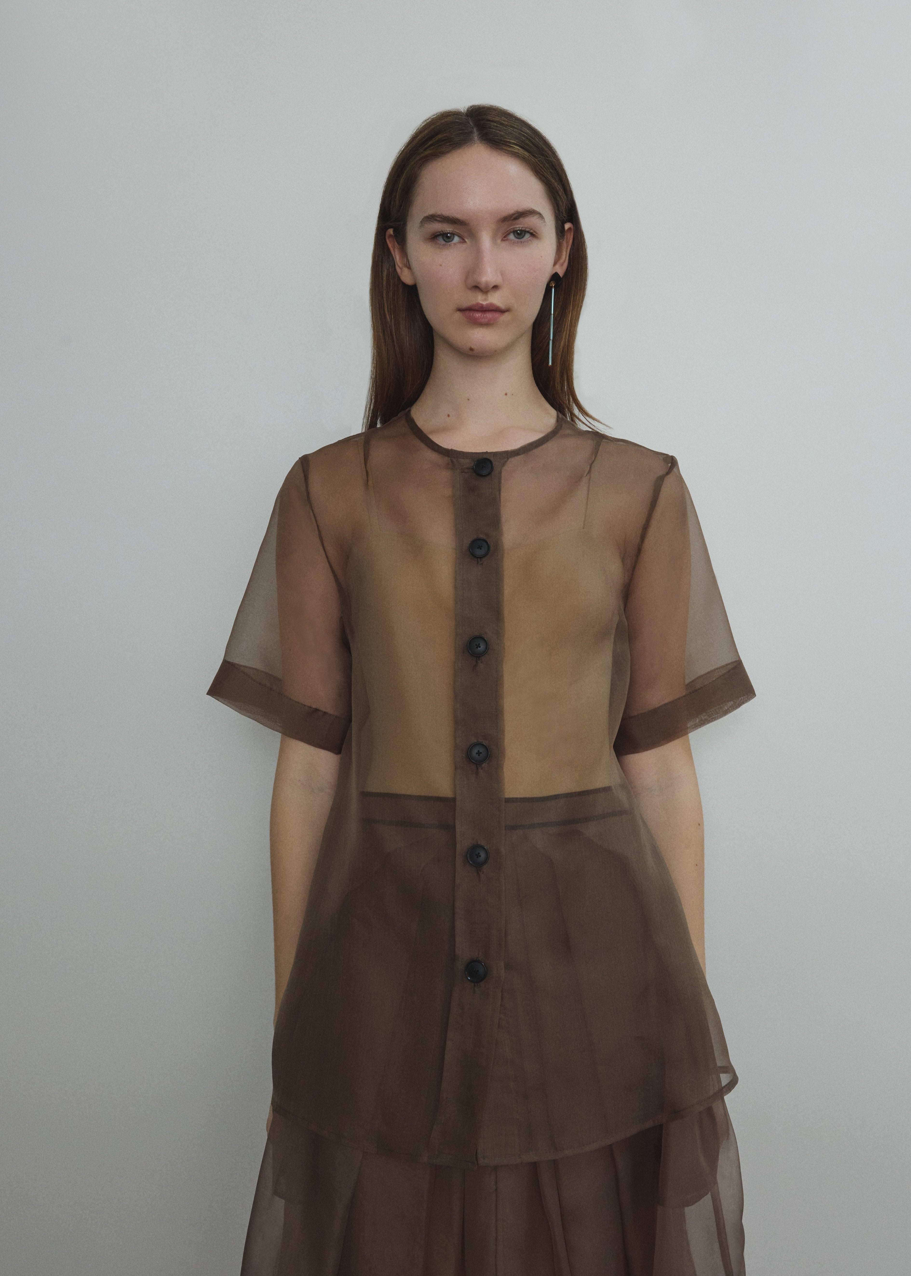 Front view of a model wearing the mushroom silk organza Kamperett Jette Tee, an oversized reversible top with wide button placket.