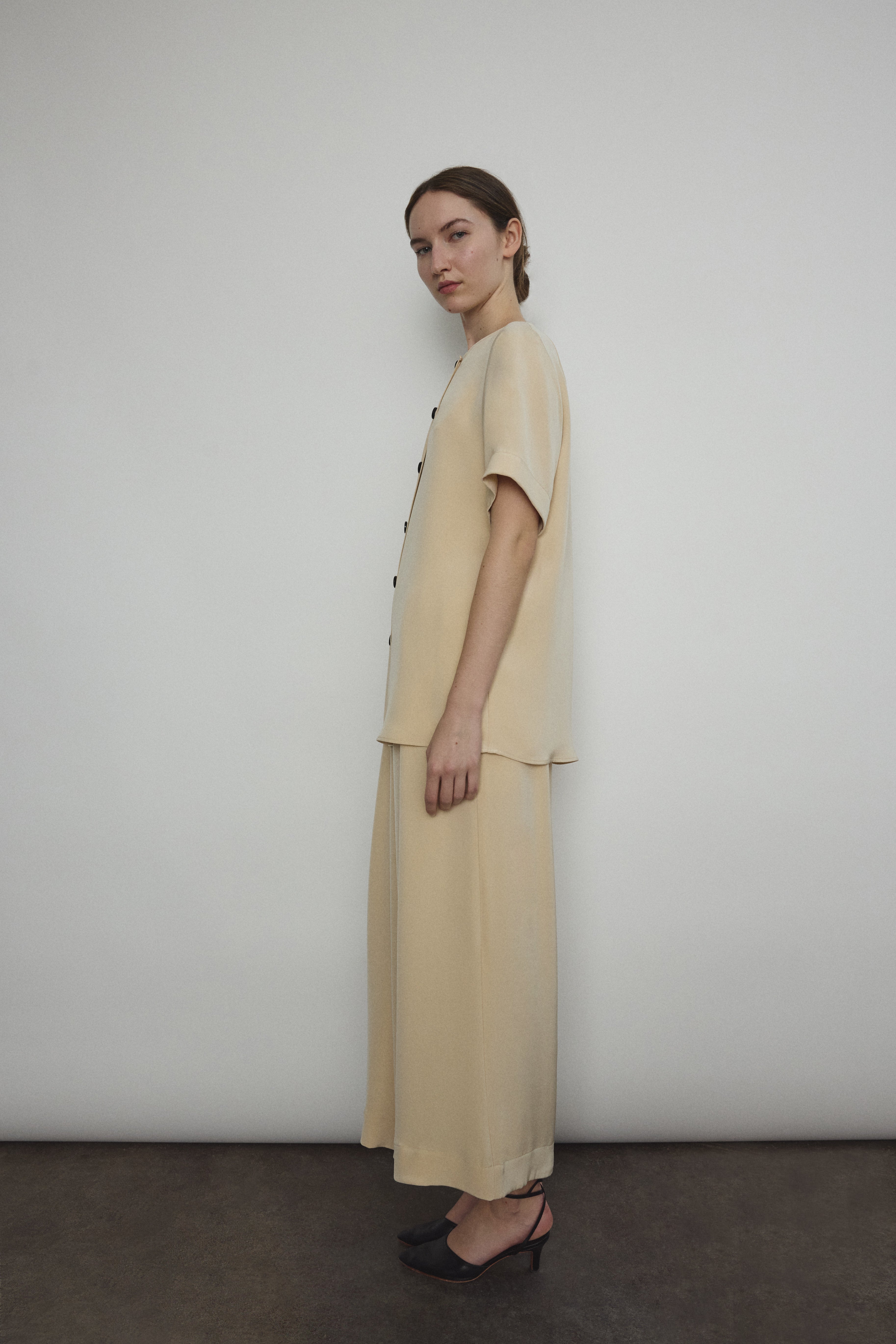Editorial image of a model in the beige silk crepe Kamperett Jette Tee.
