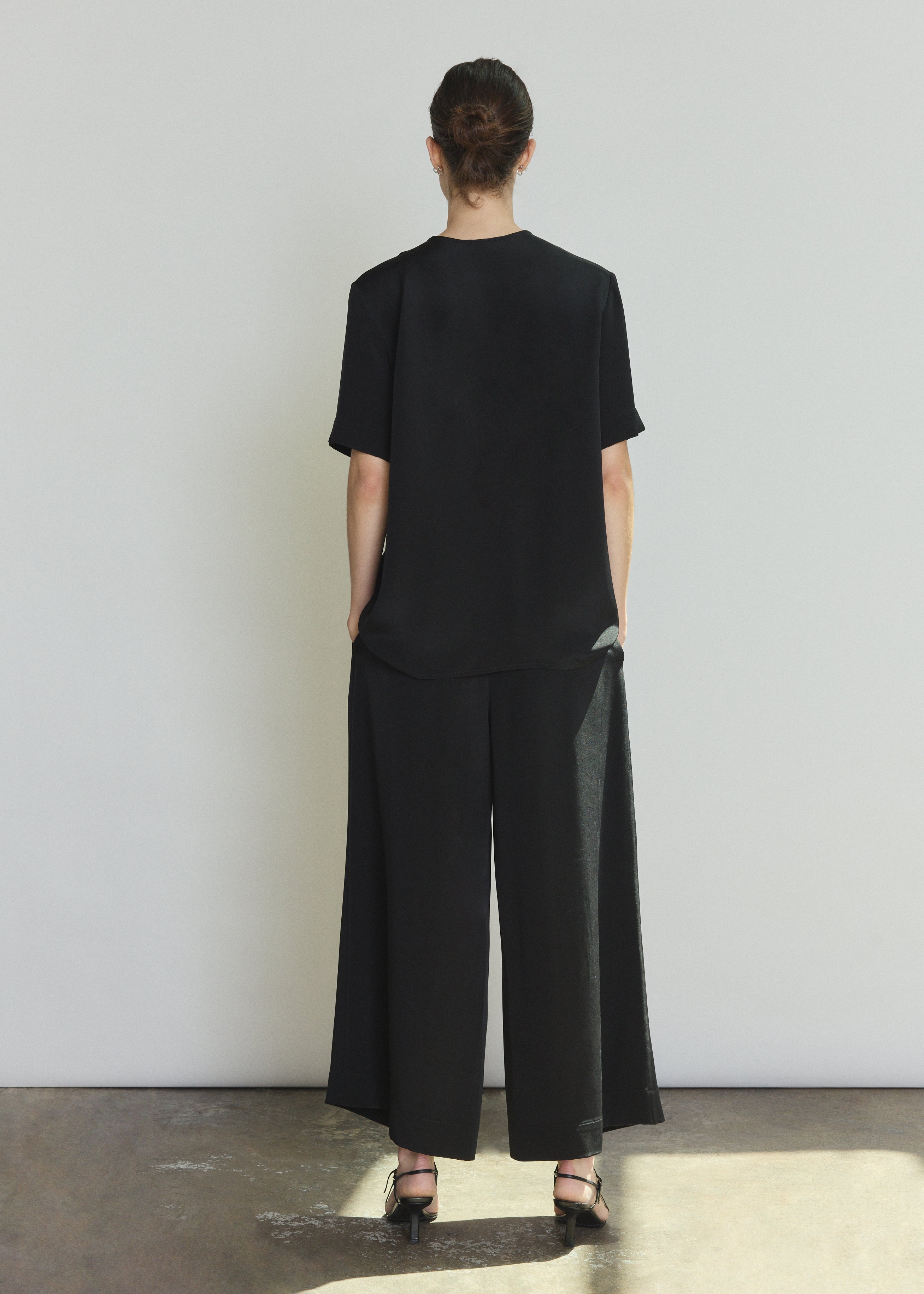Back view of the black silk crepe Kamperett Jette Silk Crepe Tee showing the reversible construction and shoulder darts.