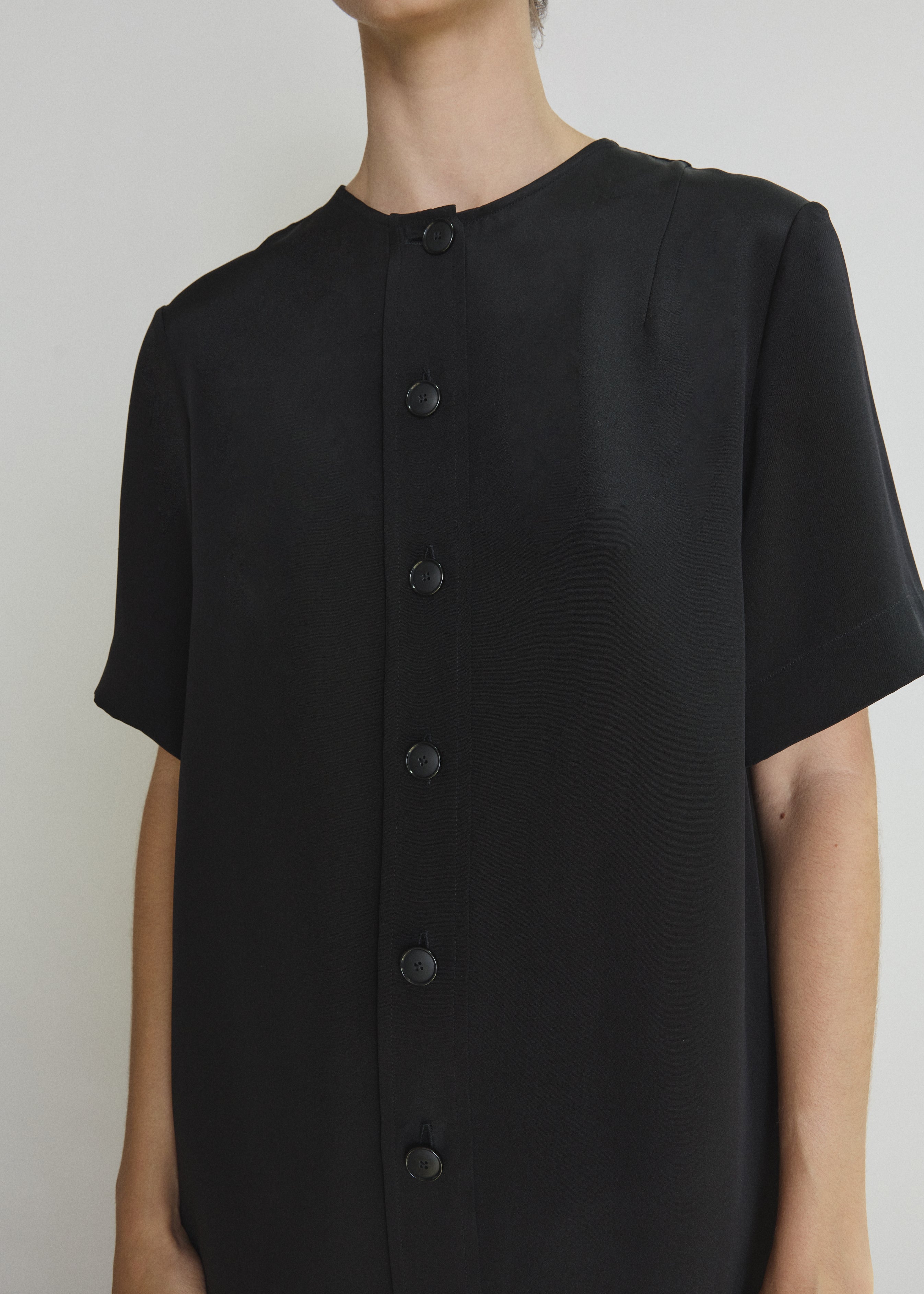 Detail of the black silk crepe Kamperett Jette Silk Crepe Tee showing the wide button placket and fabric.