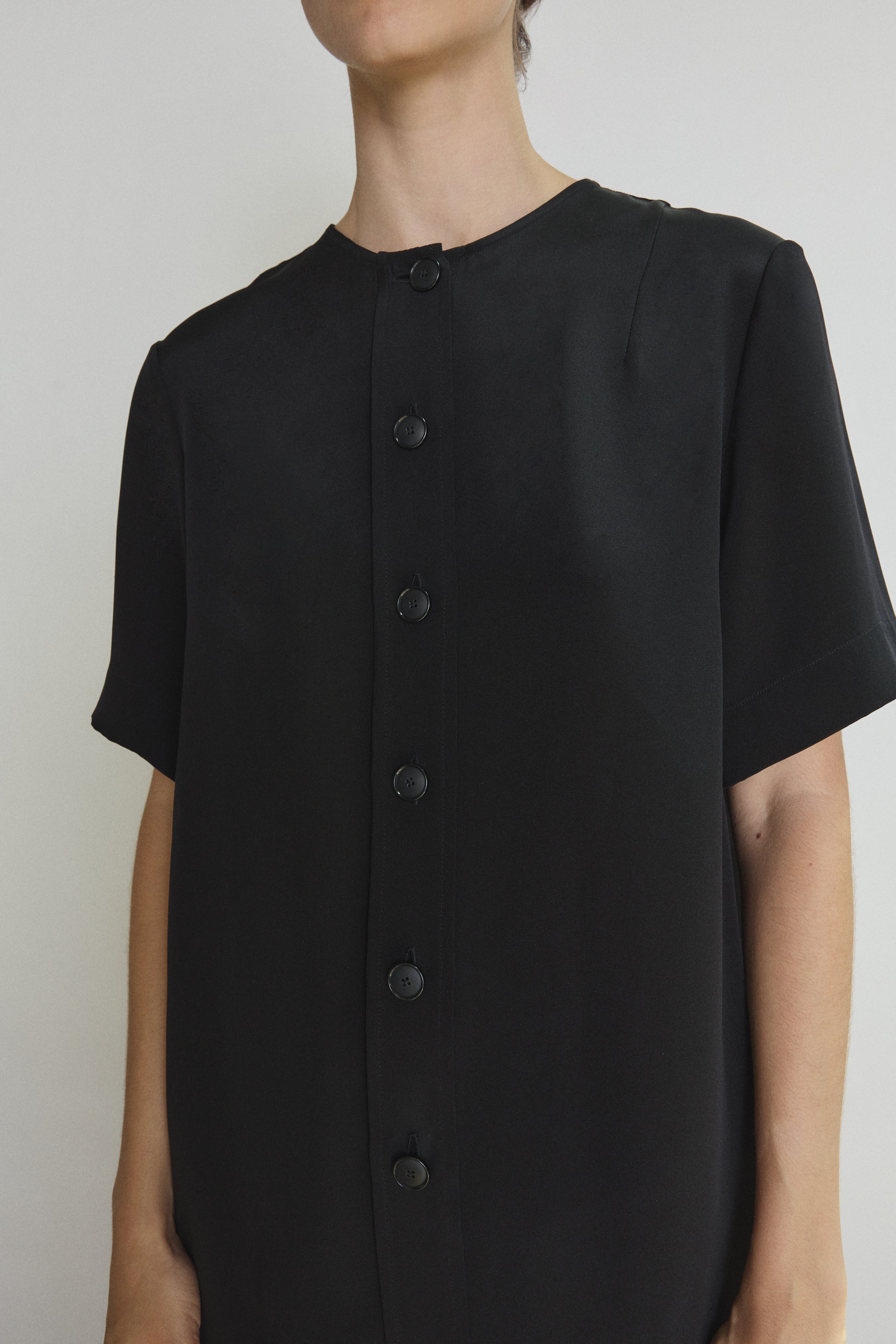 Detail of the black silk crepe Kamperett Jette Silk Crepe Tee showing the wide button placket and fabric.