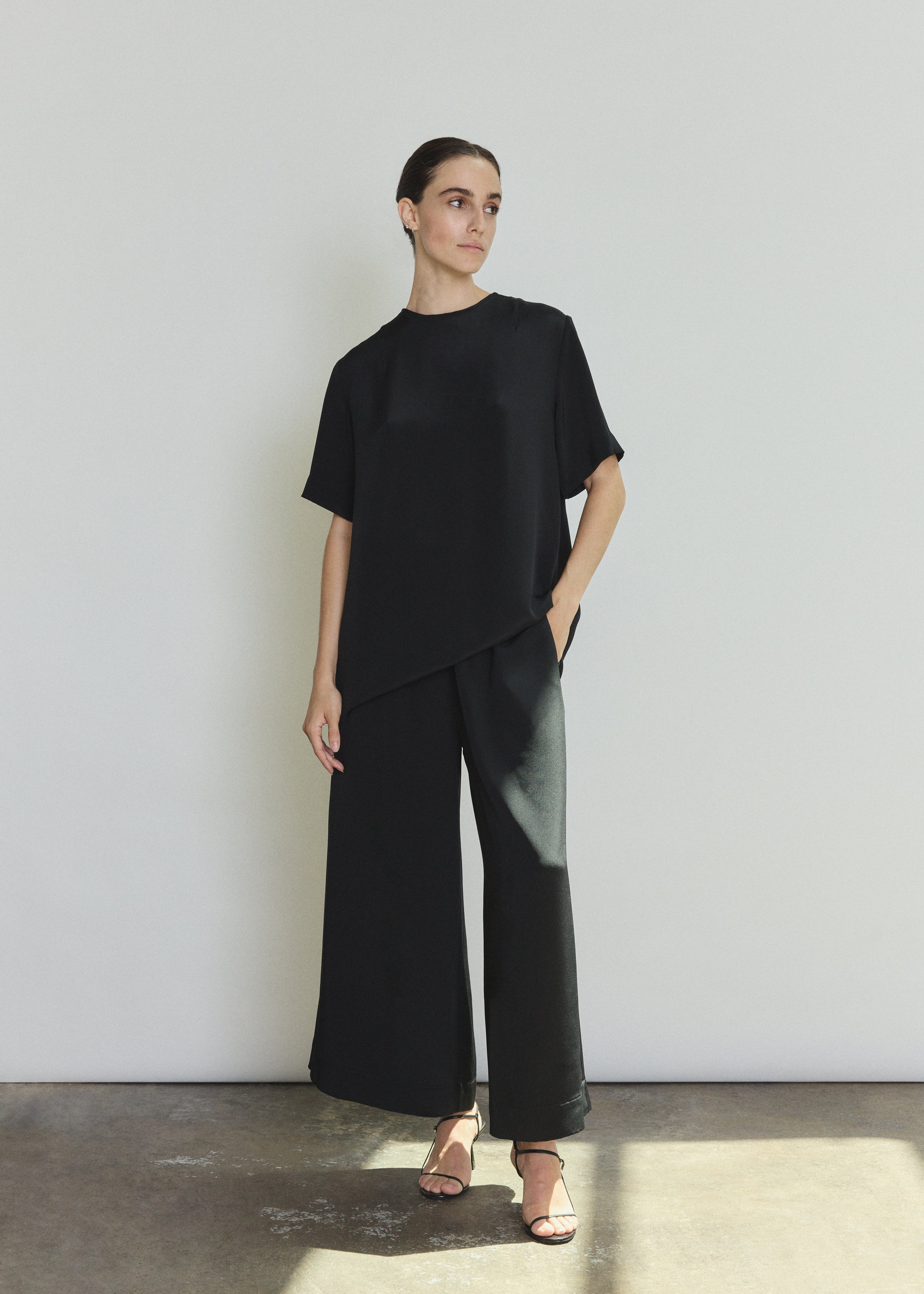 Editorial image of a model wearing the black Kamperett Jette Silk Crepe Tee, a modern minimalist silk crepe top.