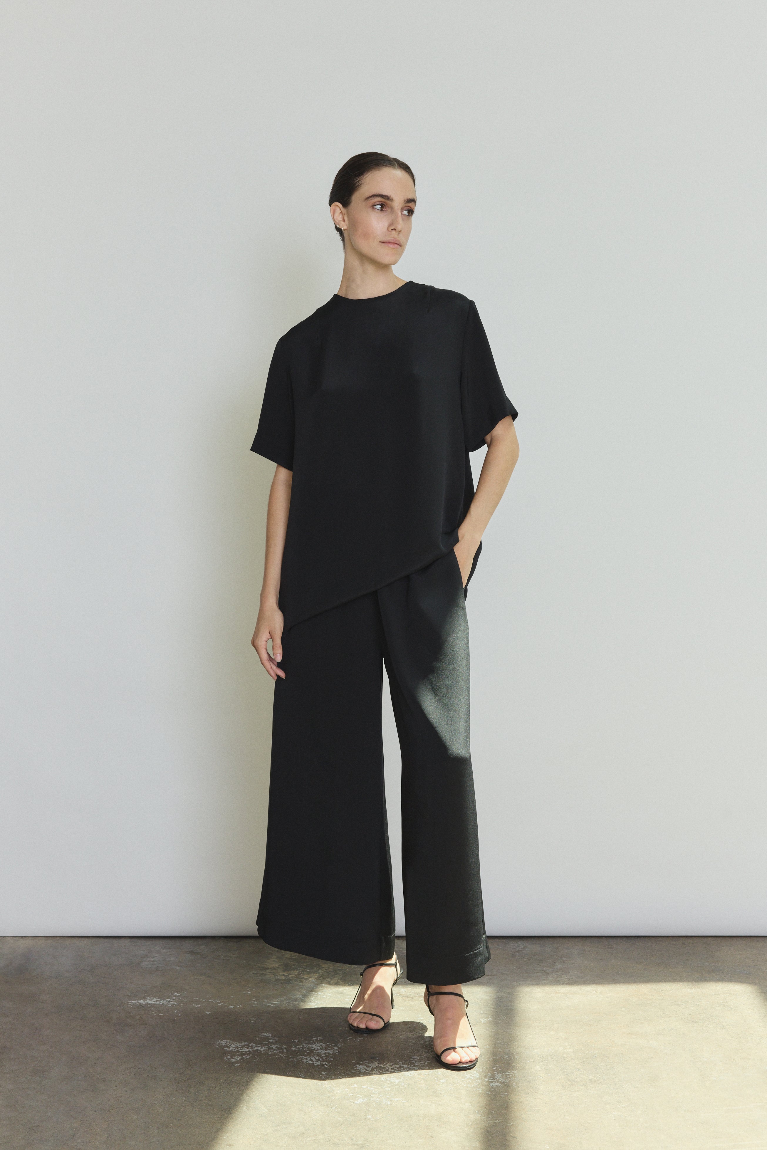 Editorial image of a model wearing the black Kamperett Jette Silk Crepe Tee, a modern minimalist silk crepe top.