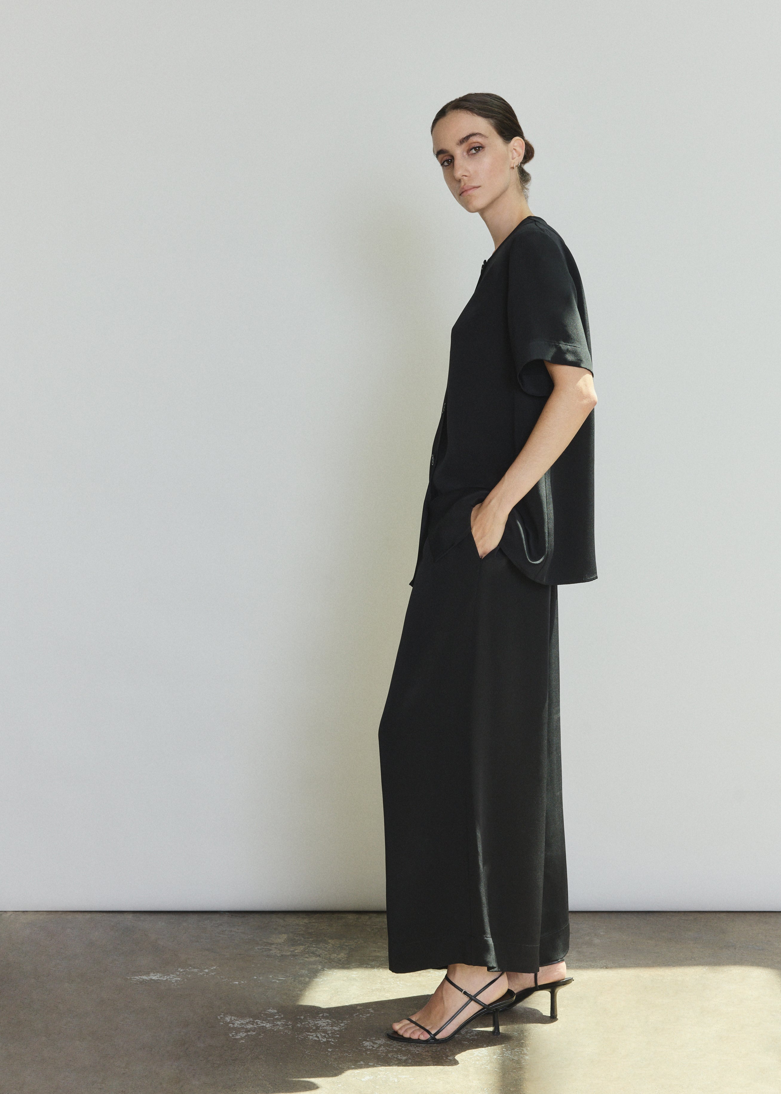 Side view of the black silk crepe Kamperett Jette Silk Crepe Tee showing the relaxed oversized silhouette.