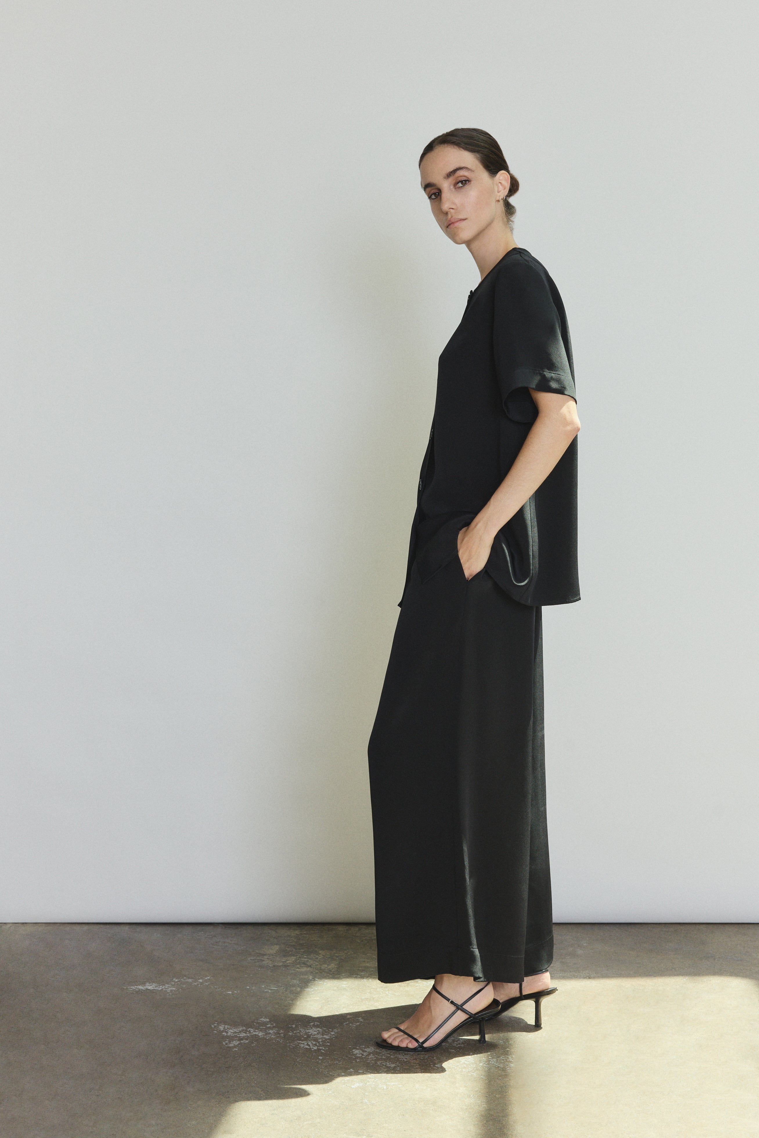Side view of the black silk crepe Kamperett Jette Silk Crepe Tee showing the relaxed oversized silhouette.
