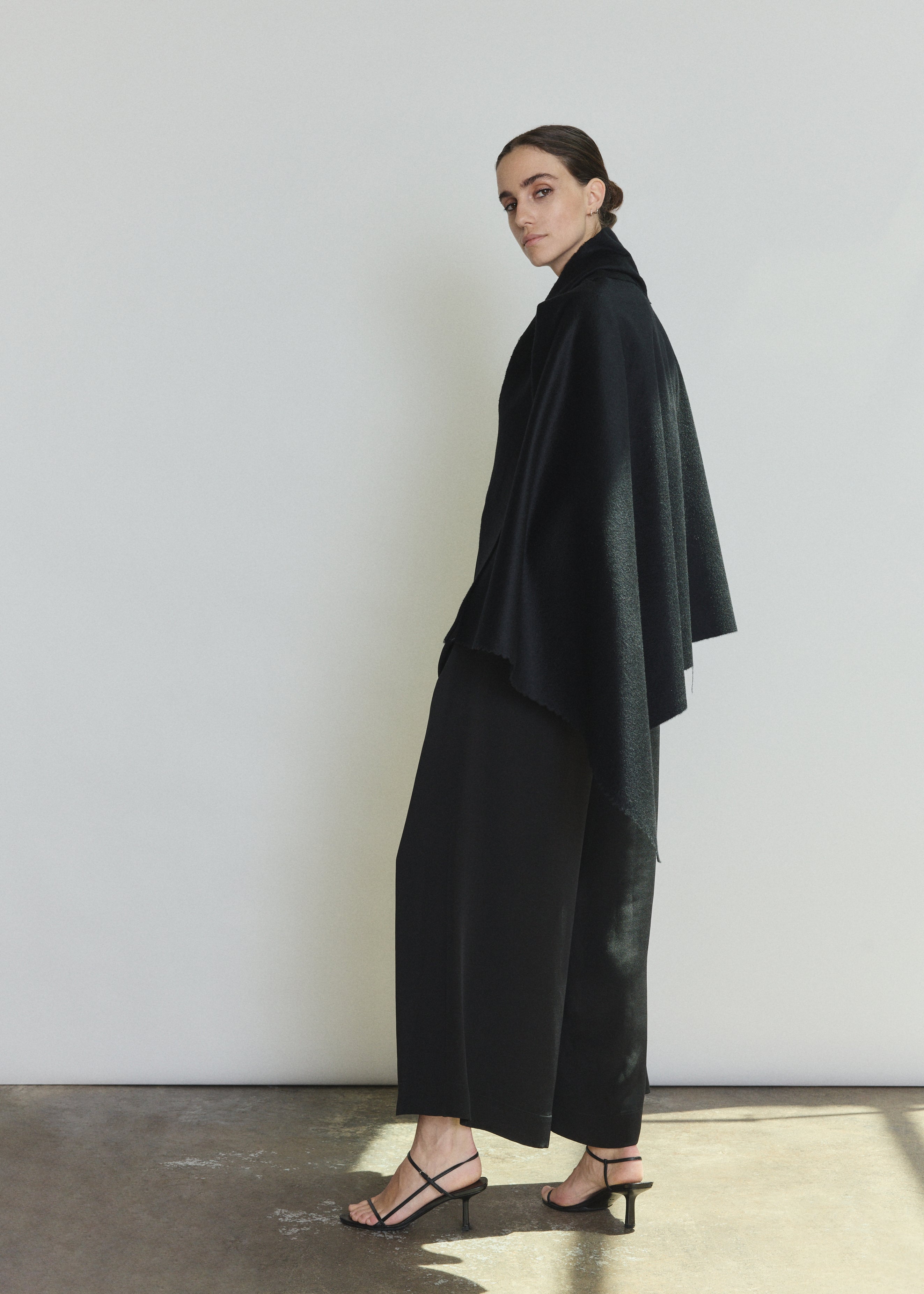 Back view of the black cashmere Kamperett Joan Cape showing the selvedge edges and full silhouette.