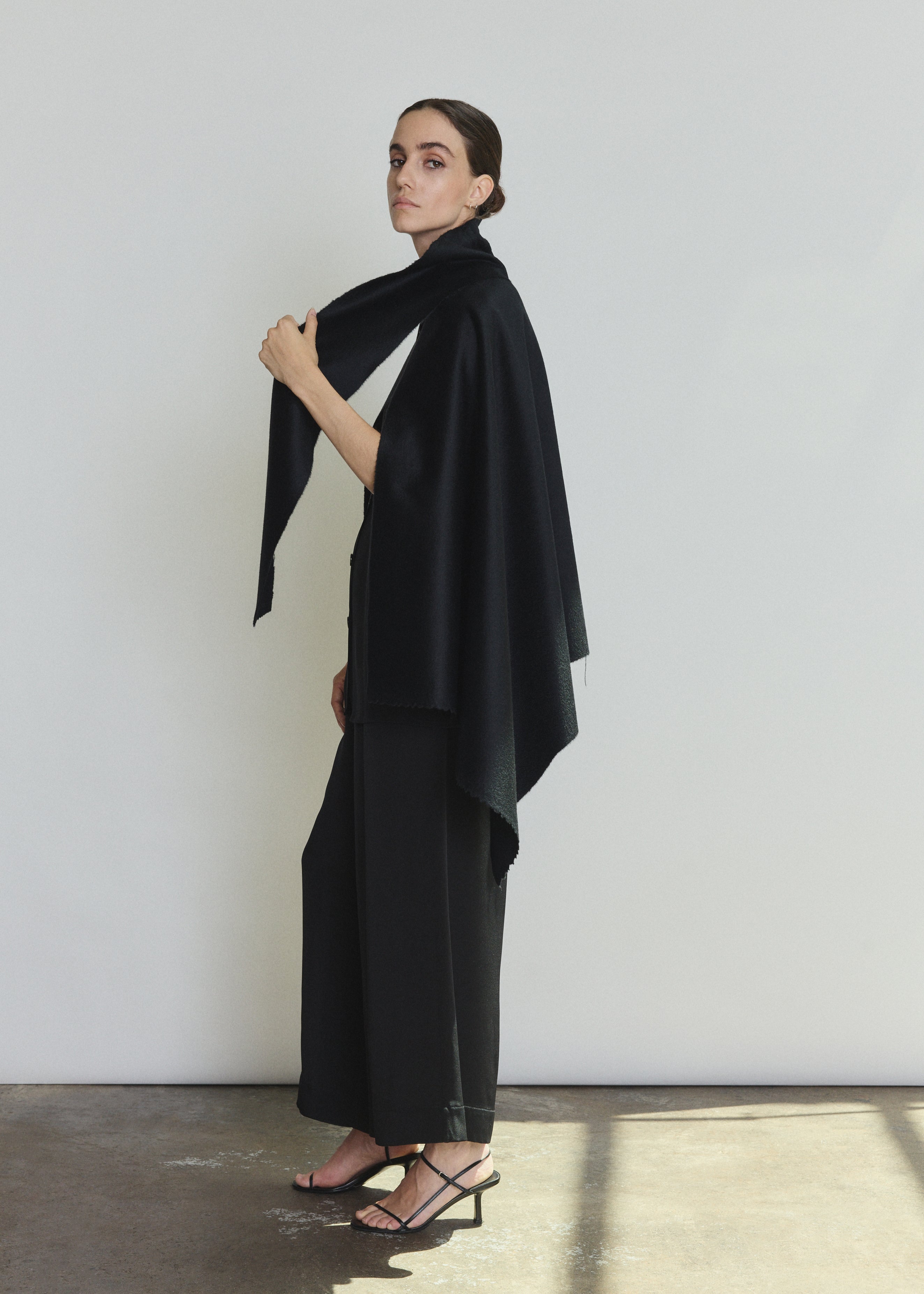 Detail of the black cashmere Kamperett Joan Cape showing the attached scarf and selvedge finishing.