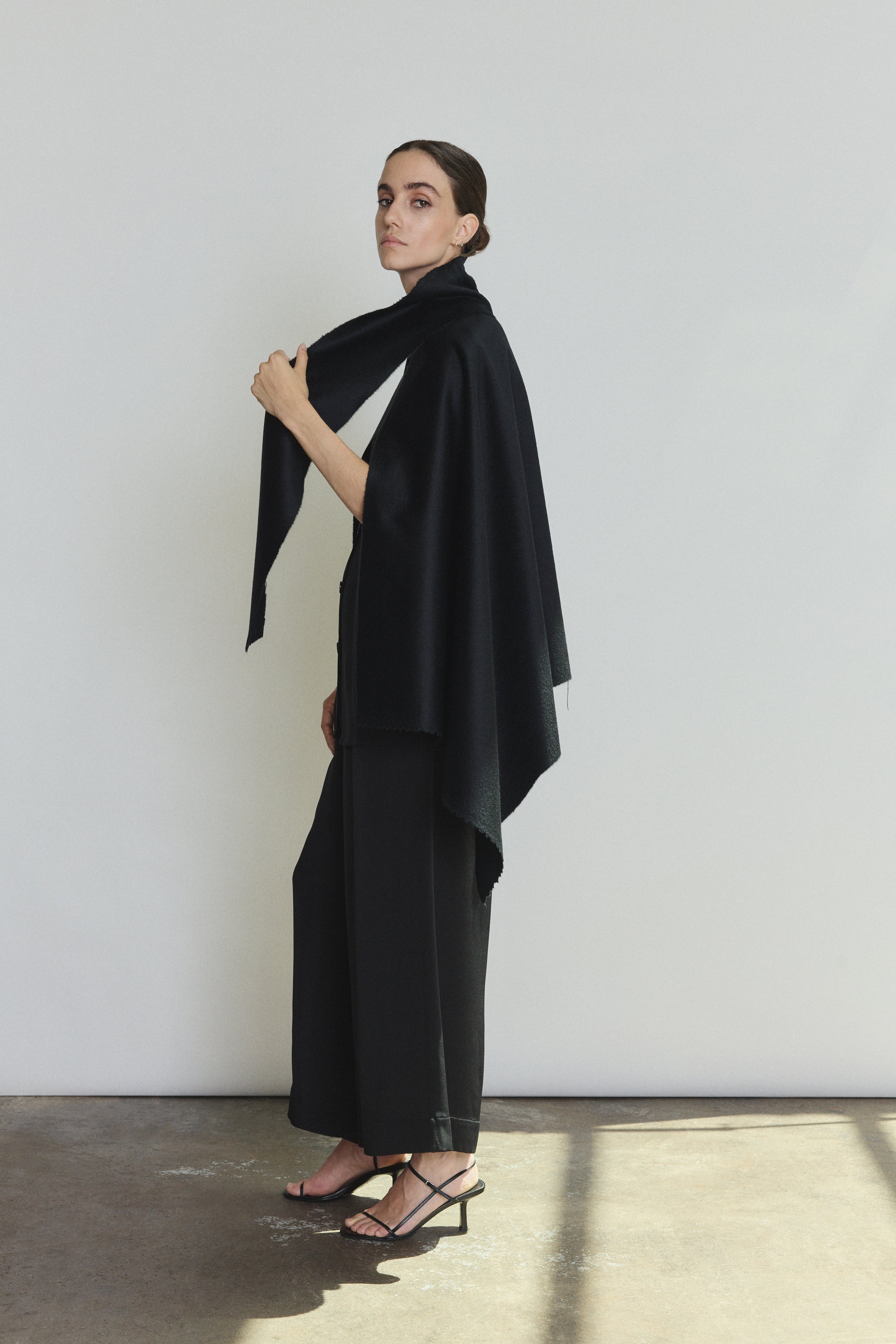 Detail of the black cashmere Kamperett Joan Cape showing the attached scarf and selvedge finishing.