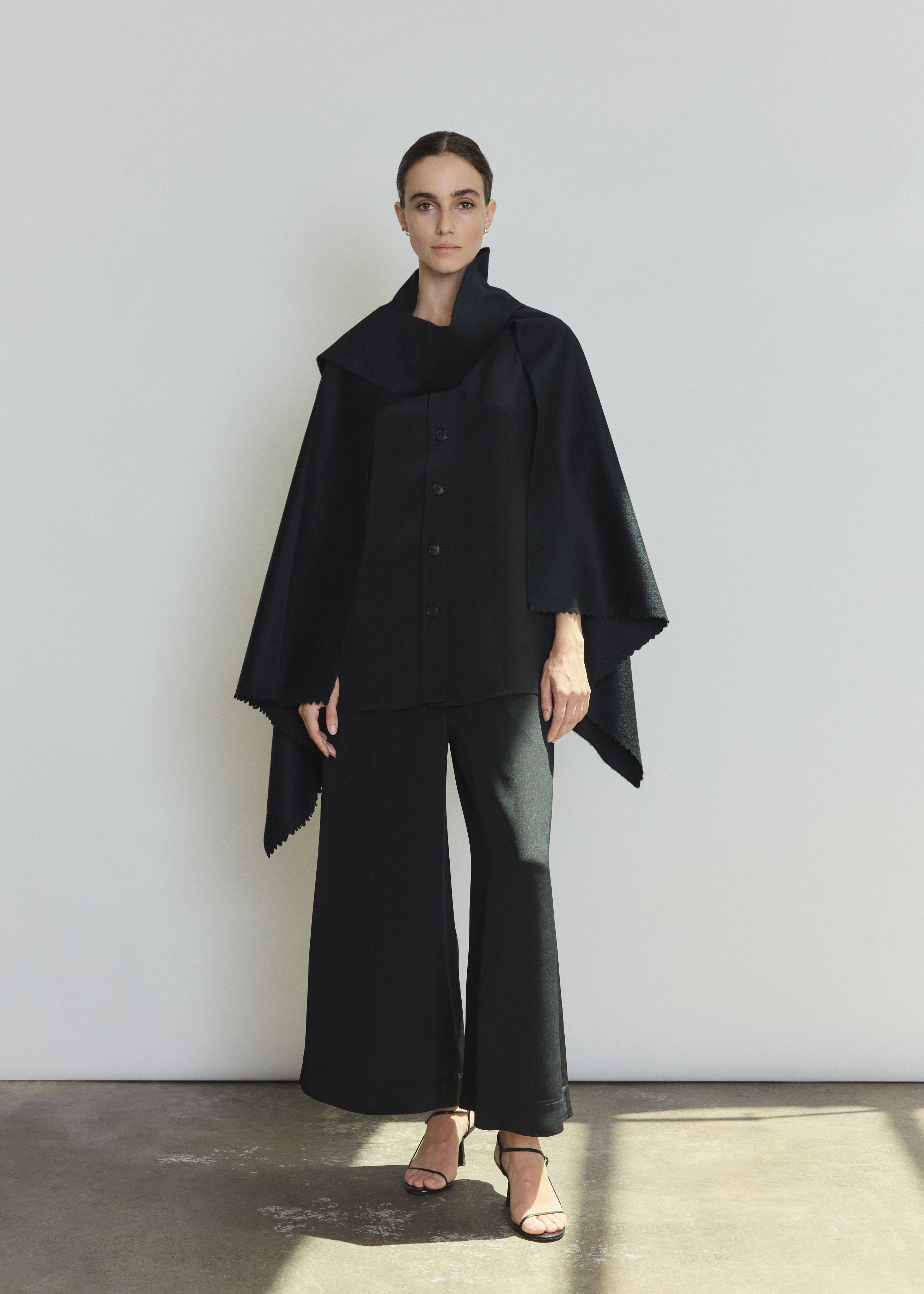 Front view of a model wearing the black Italian cashmere Kamperett Joan Cape, styled with the Jette Silk Crepe Tee and Alix Silk Crepe Pant.