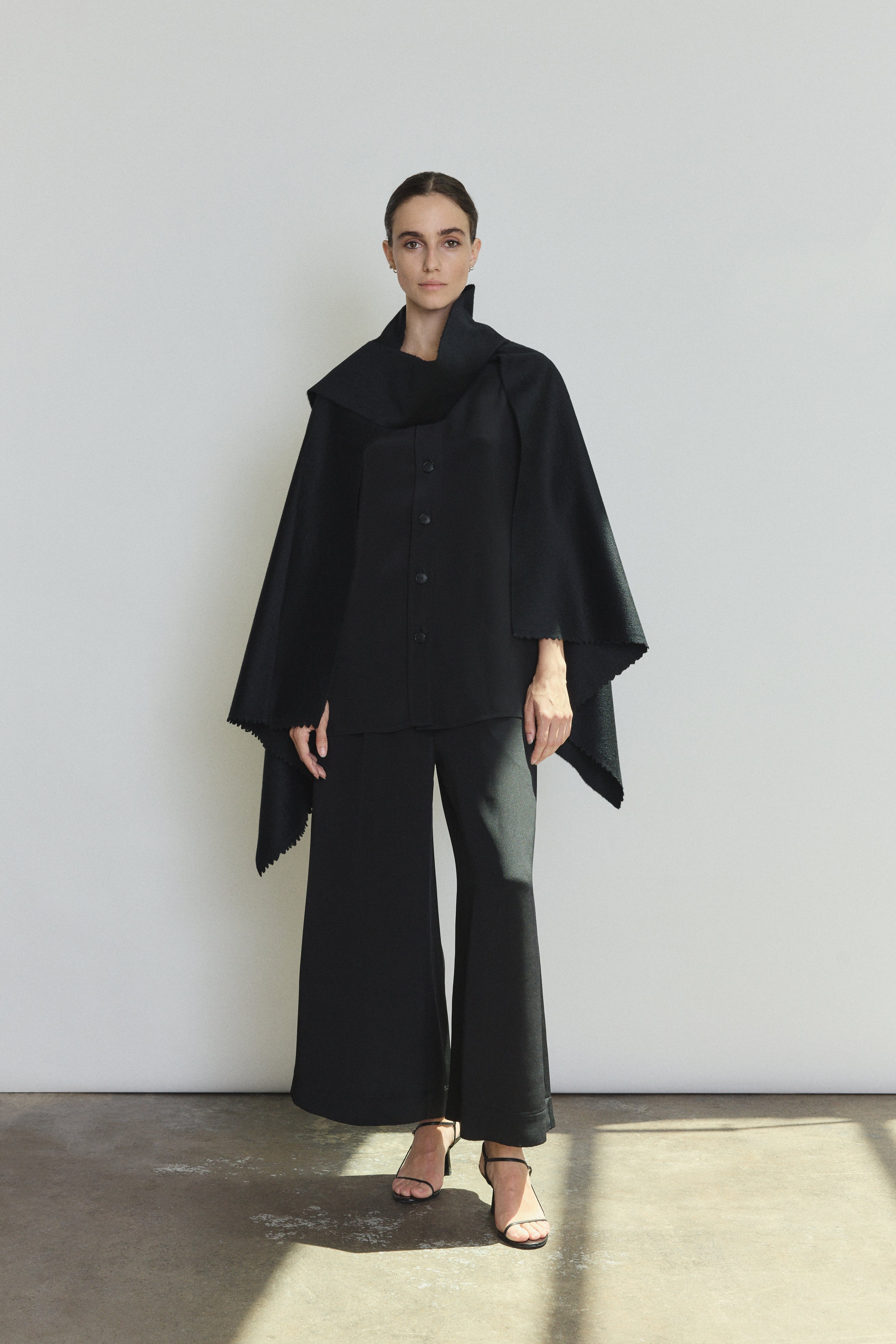 Front view of a model wearing the black Italian cashmere Kamperett Joan Cape, styled with the Jette Silk Crepe Tee and Alix Silk Crepe Pant.