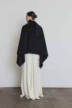 Editorial image of the black Kamperett Joan Cashmere Cape styled with the Ray Gown in Alabaster.
