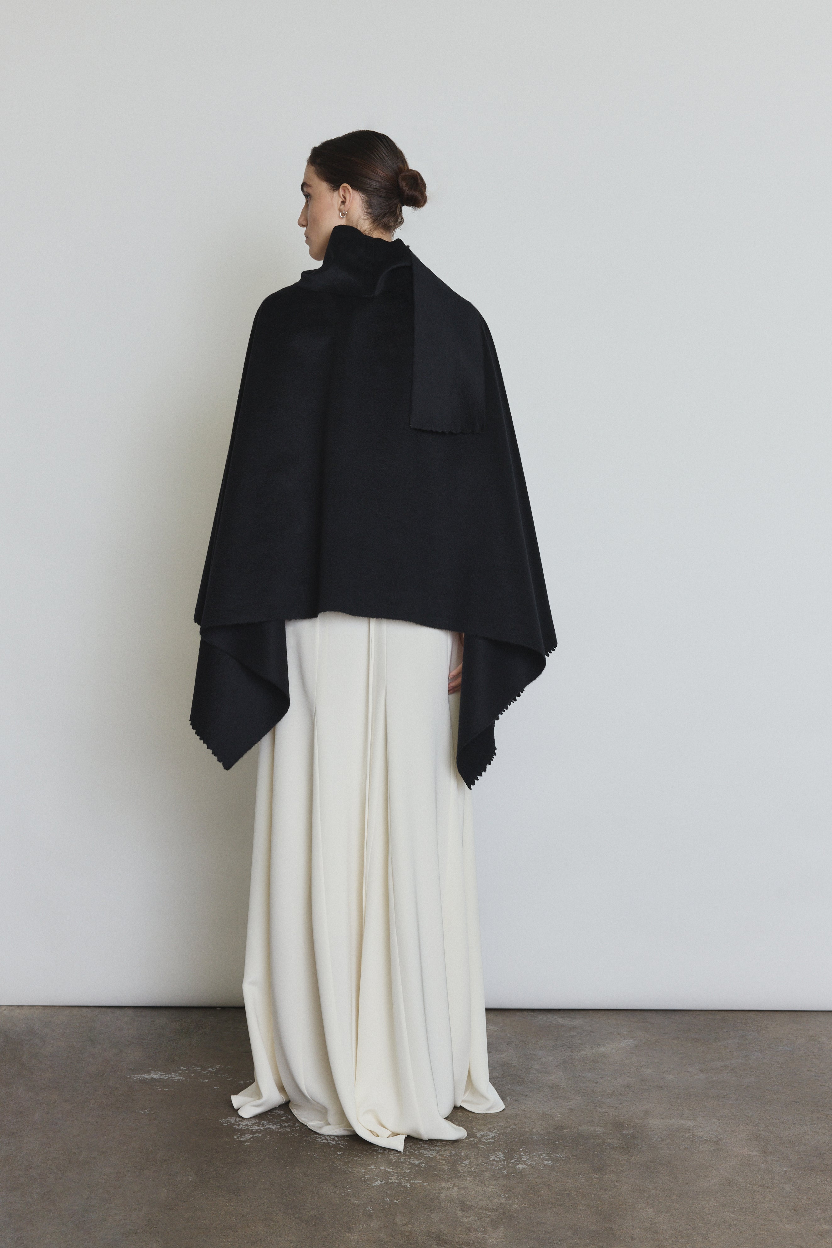 Editorial image of the black Kamperett Joan Cashmere Cape styled with the Ray Gown in Alabaster.