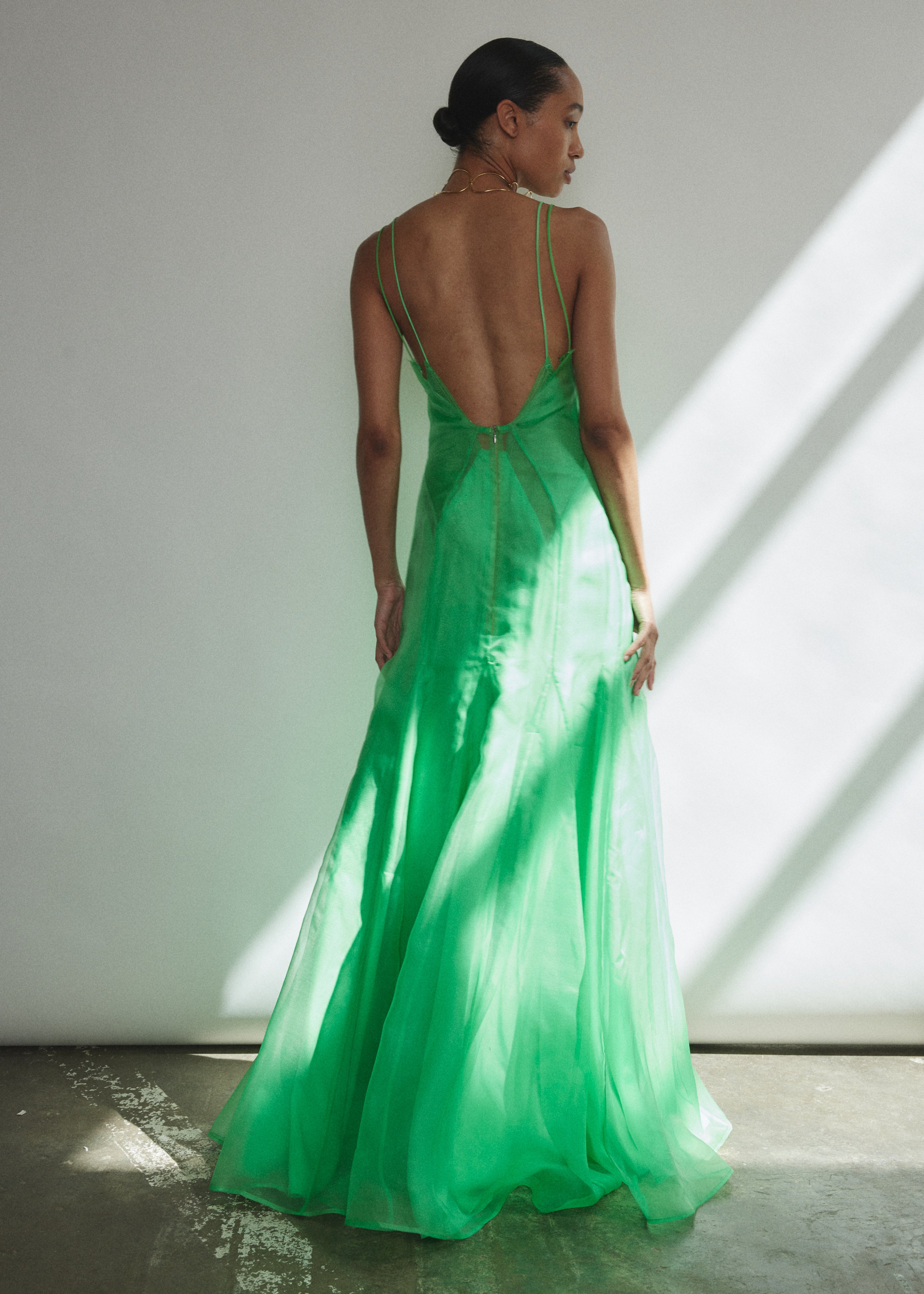 Front view of a model wearing the celadon silk organza Kamperett Lalique Gown, a sheer V-neck maxi with multi-godet skirt and corded straps.