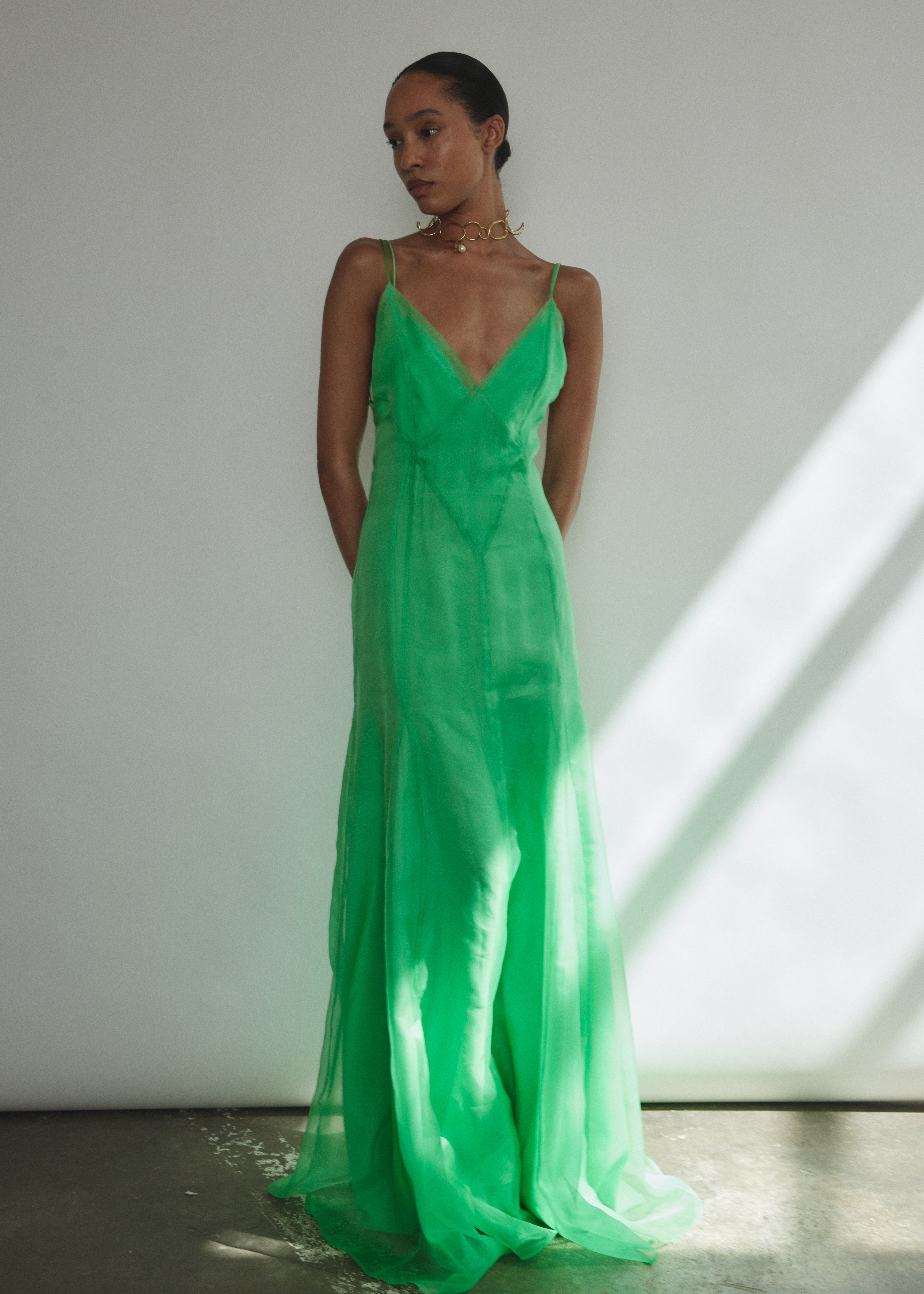 Side view of the celadon silk organza Kamperett Lalique Gown showing the sheer drape and multi-godet skirt.