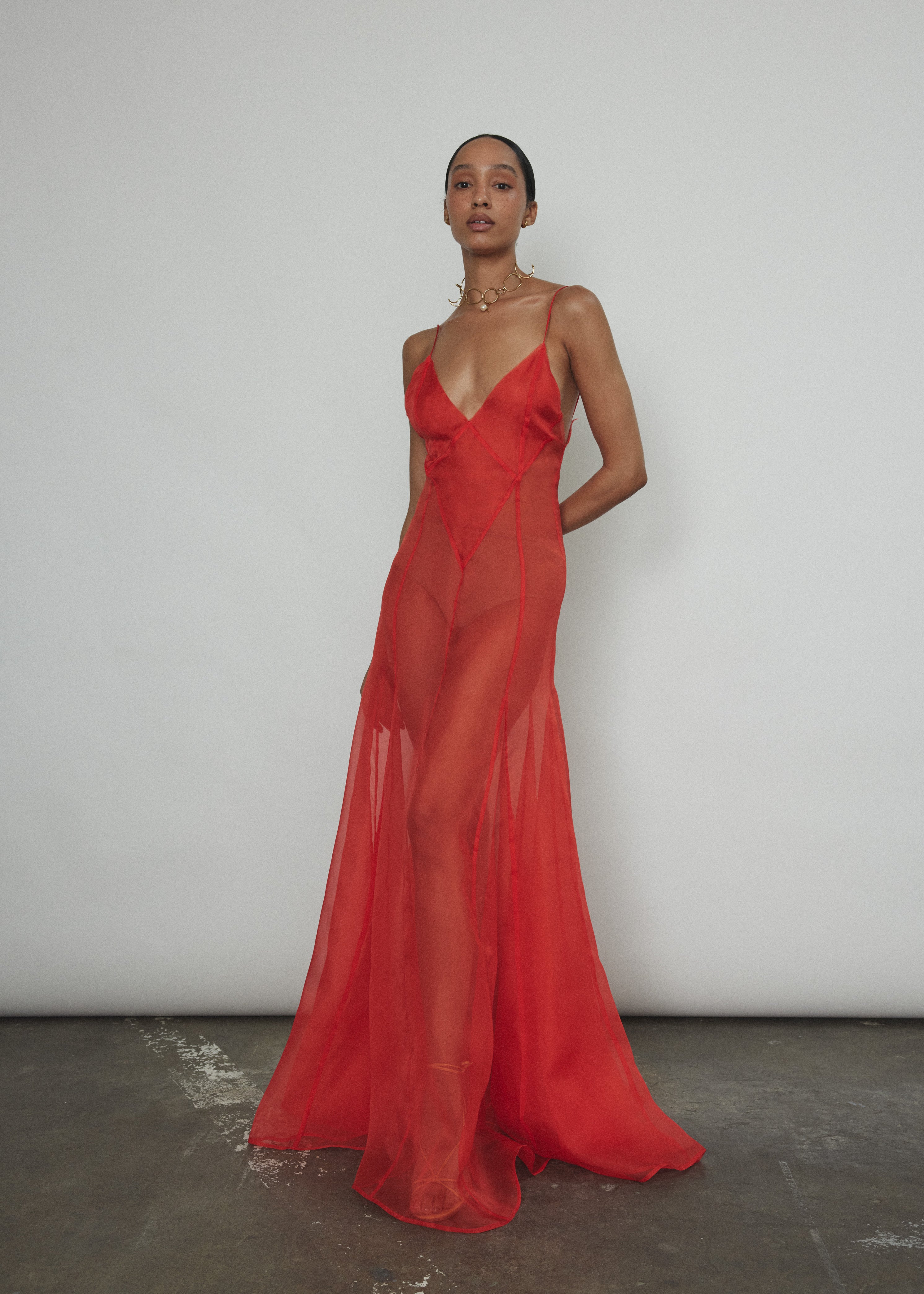 Front view of a model wearing the vermilion silk organza Kamperett Lalique Gown, a sheer V-neck maxi with multi-godet skirt.