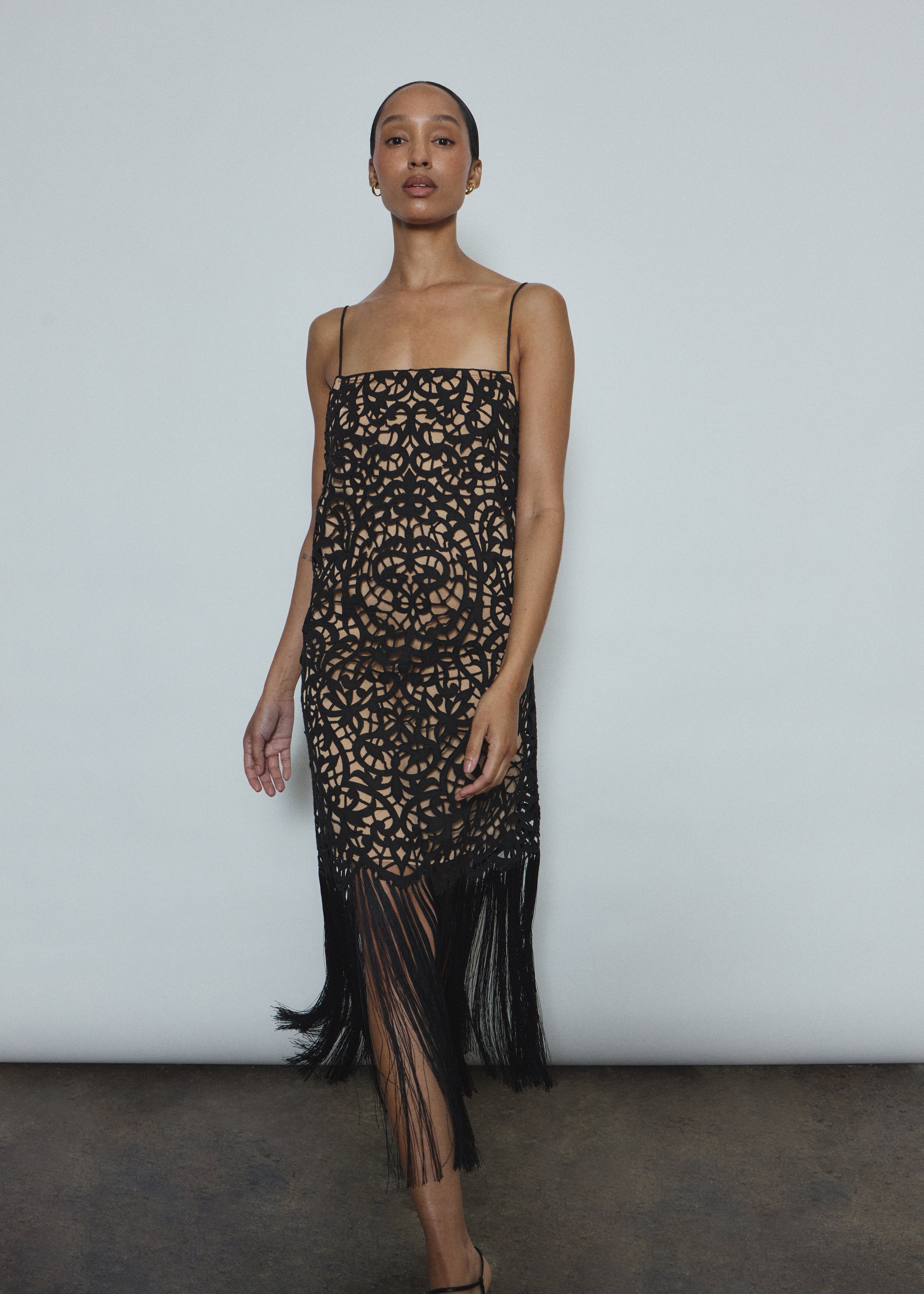 Detail of the intricately cut openwork cotton motif and hand-applied fringe on the black Kamperett Lenore Dress.